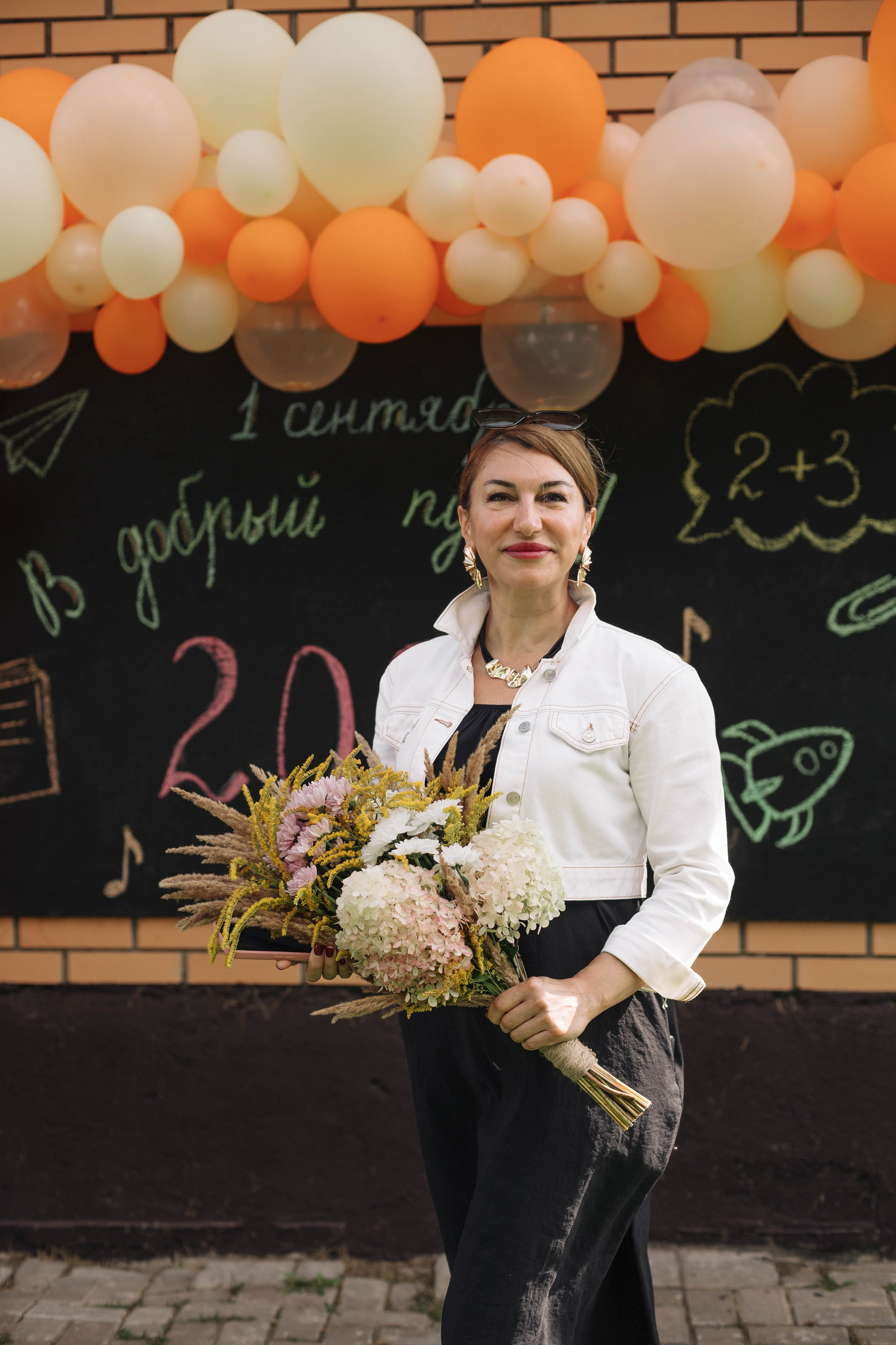Учитель с букетом цветов на первое сентбря стоит у доски