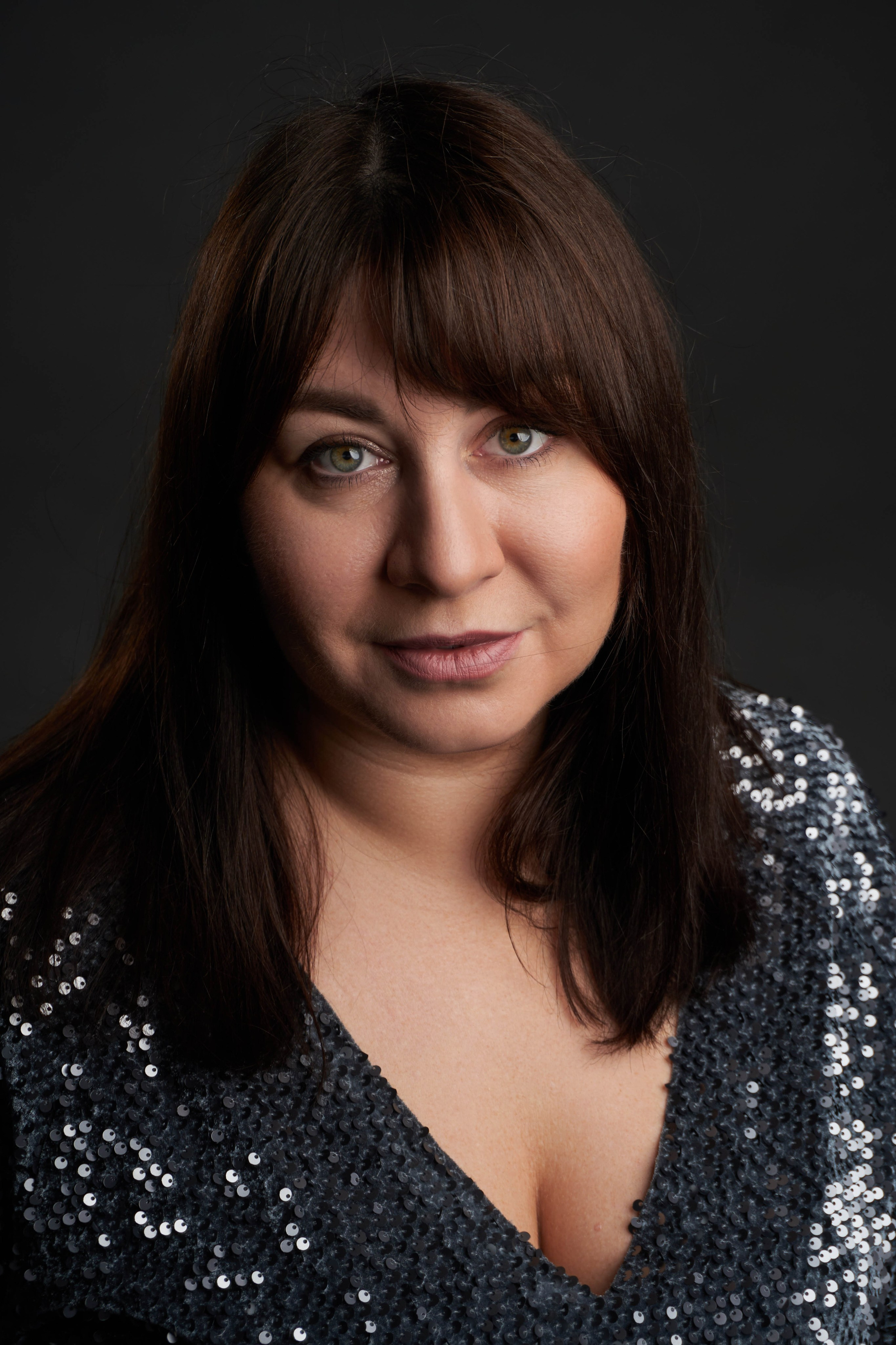 Фотосессия фигуристой девушки в темном блестящем платье