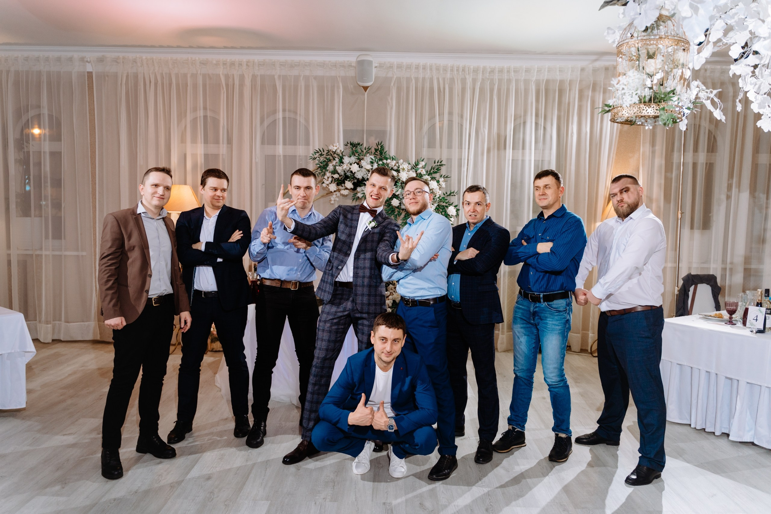 На фото жених, он улыбается, а вокруг него стоят друзья и родственники.