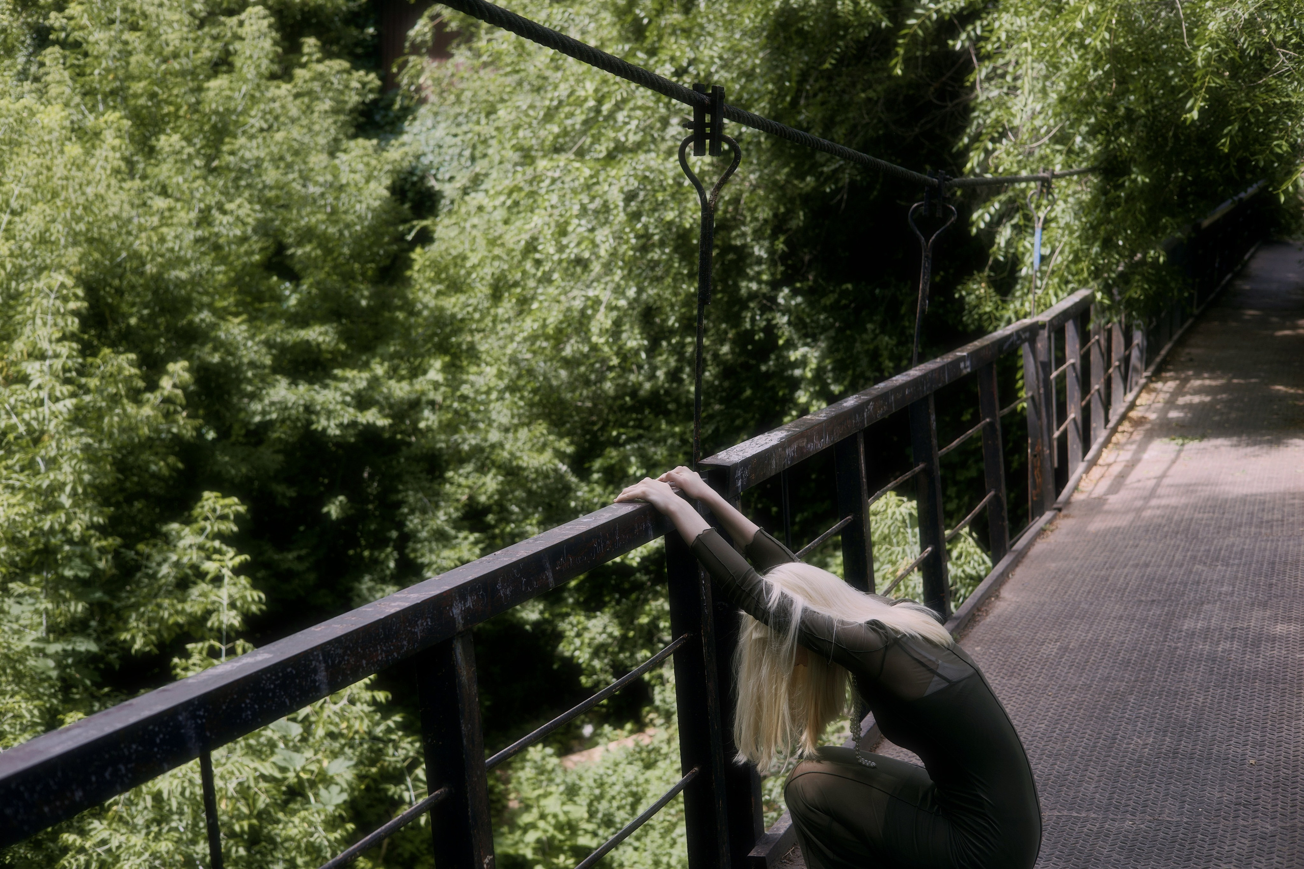 Фотосессия девушки на мосту в окружении густой зелени