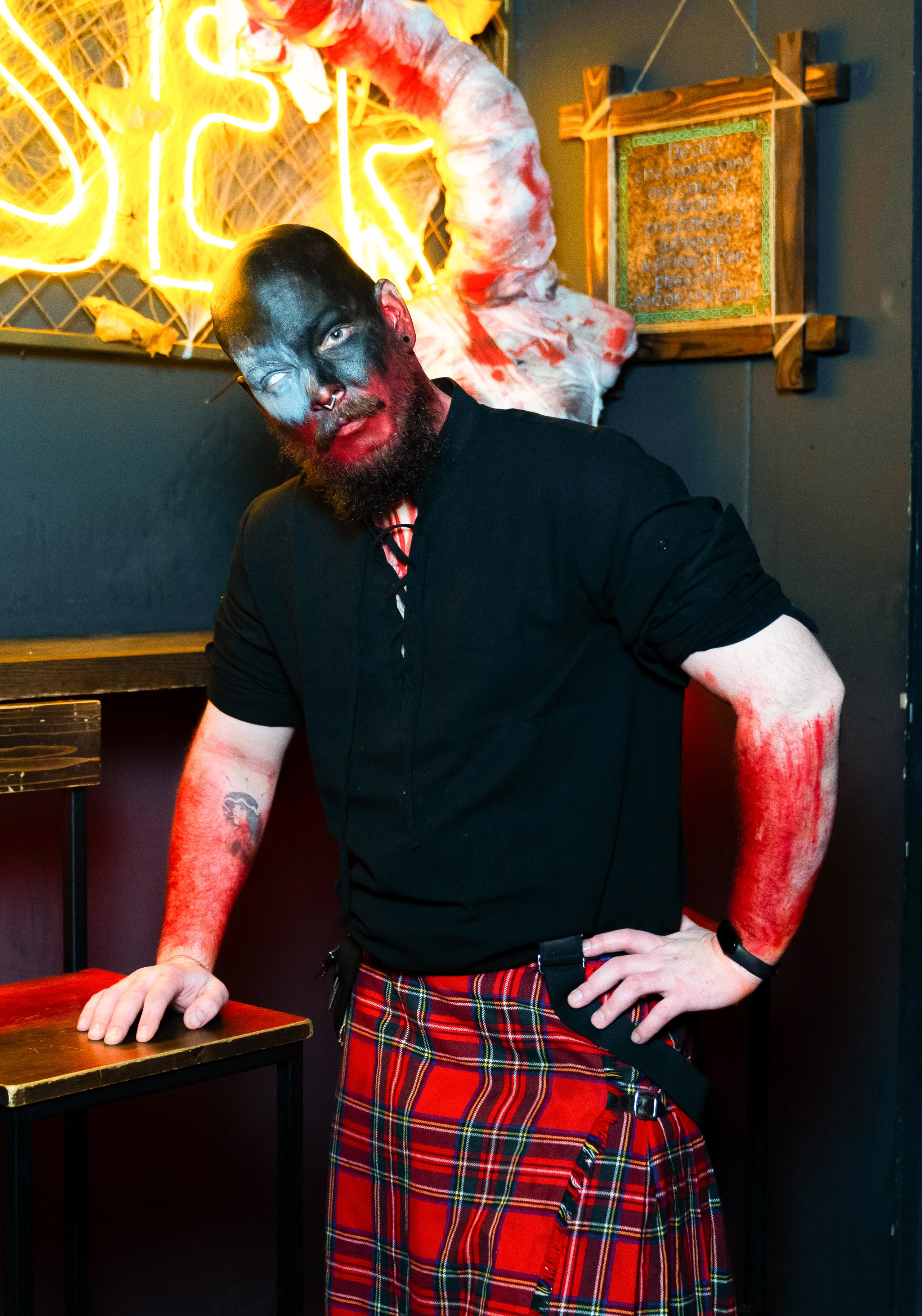 Бар Debaser. Тематическая вечеринка в баре СПб — мужчина в чёрном гриме и шотландском килте у неоновой вывески, репортажная съёмка Евгения Мальцева.