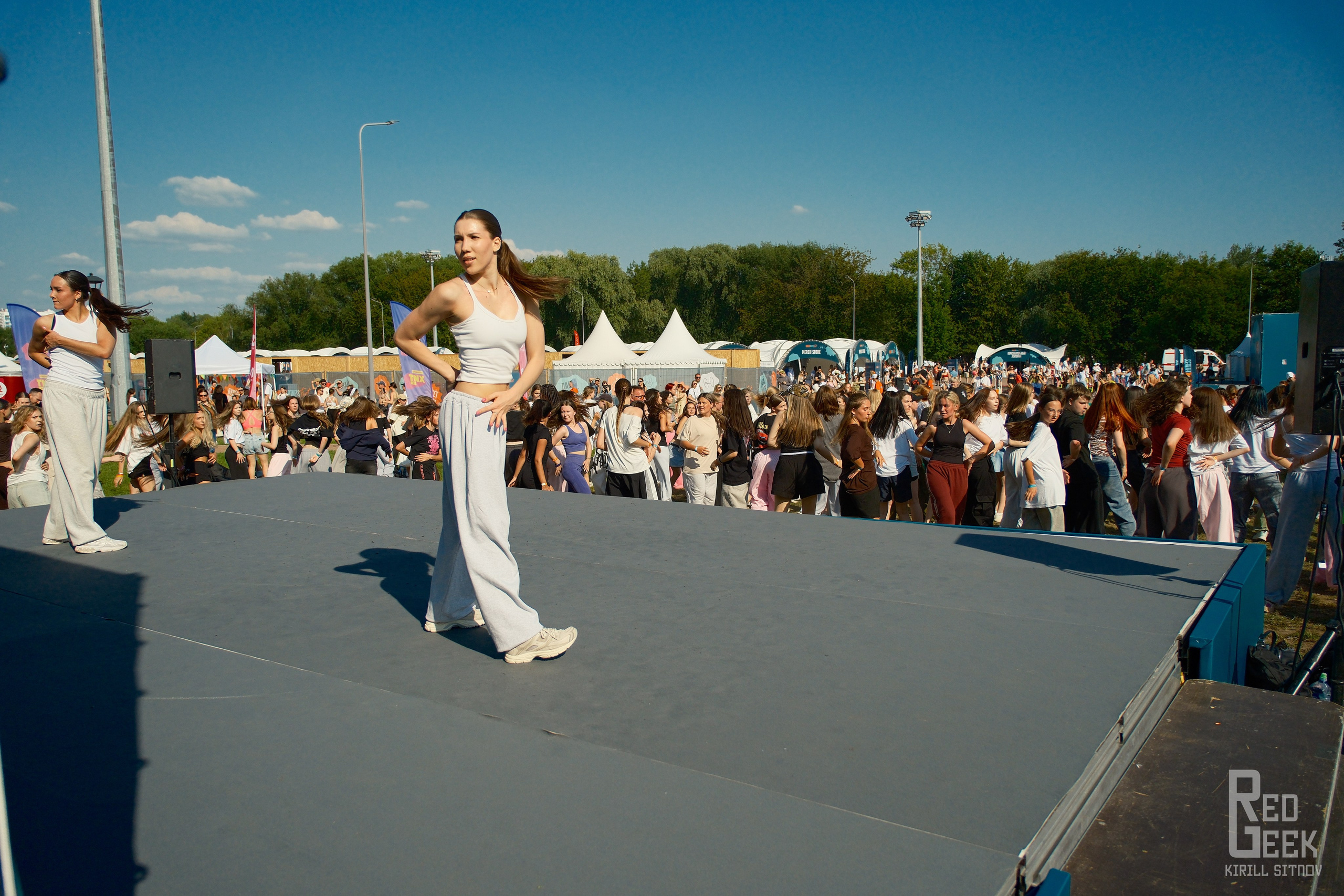 Девушка в белом демонстрирует спортивные танцы на сцене.