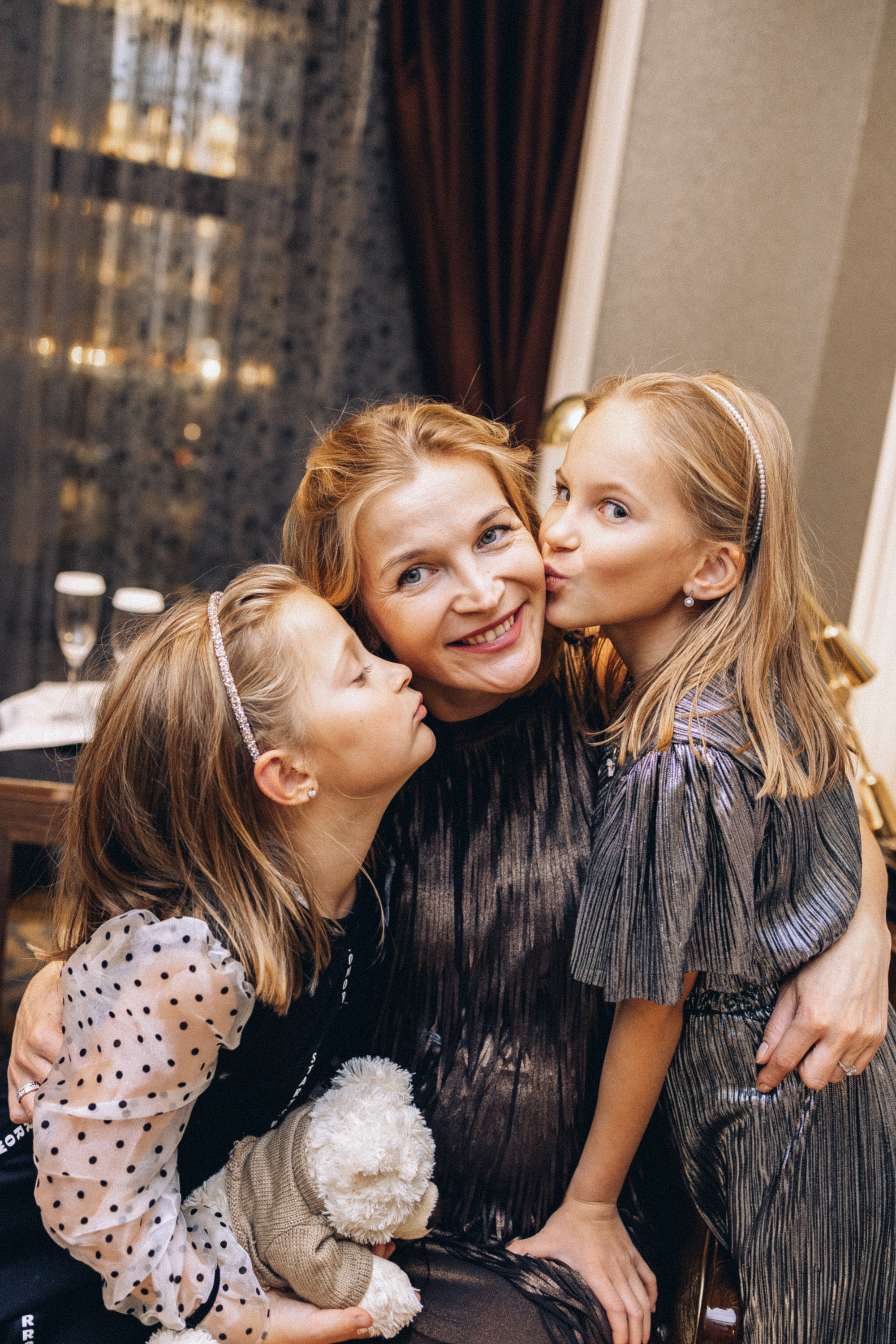 две сестры целуют маму