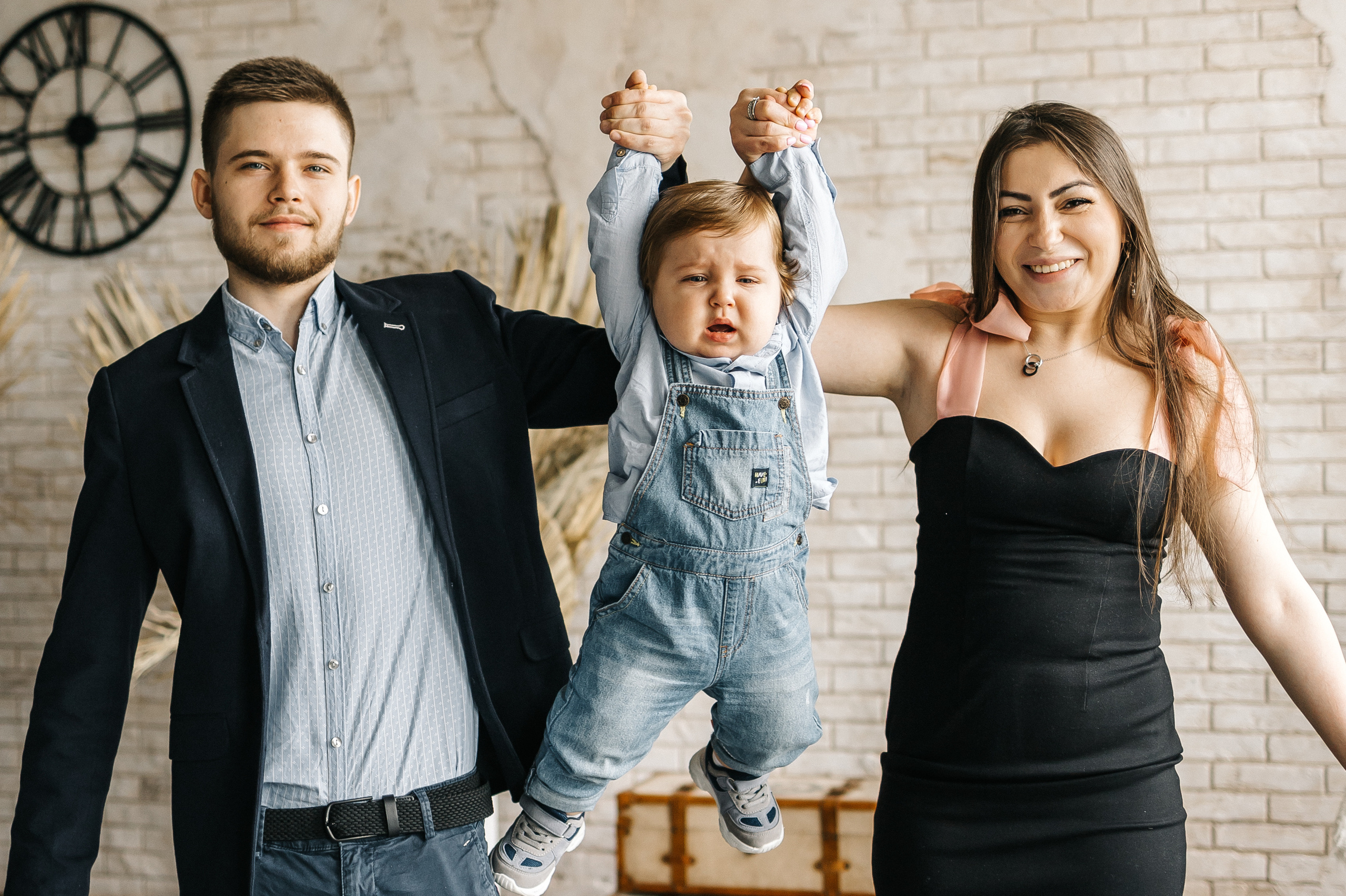 папа с мамой держат за руки ребенка