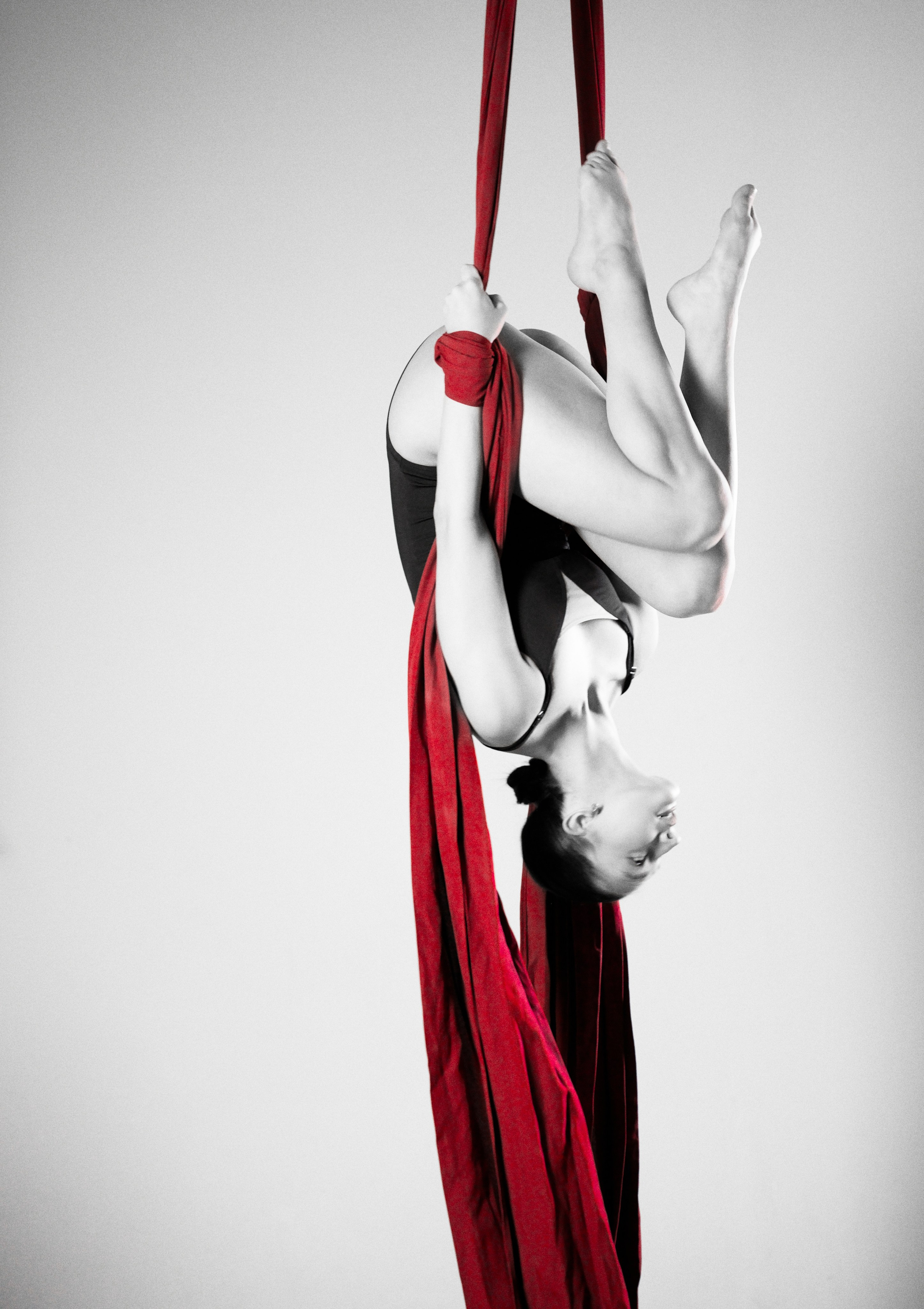 Съемка воздушной гимнастики в Тюмени: сложный перевернутый элемент на красных полотнах