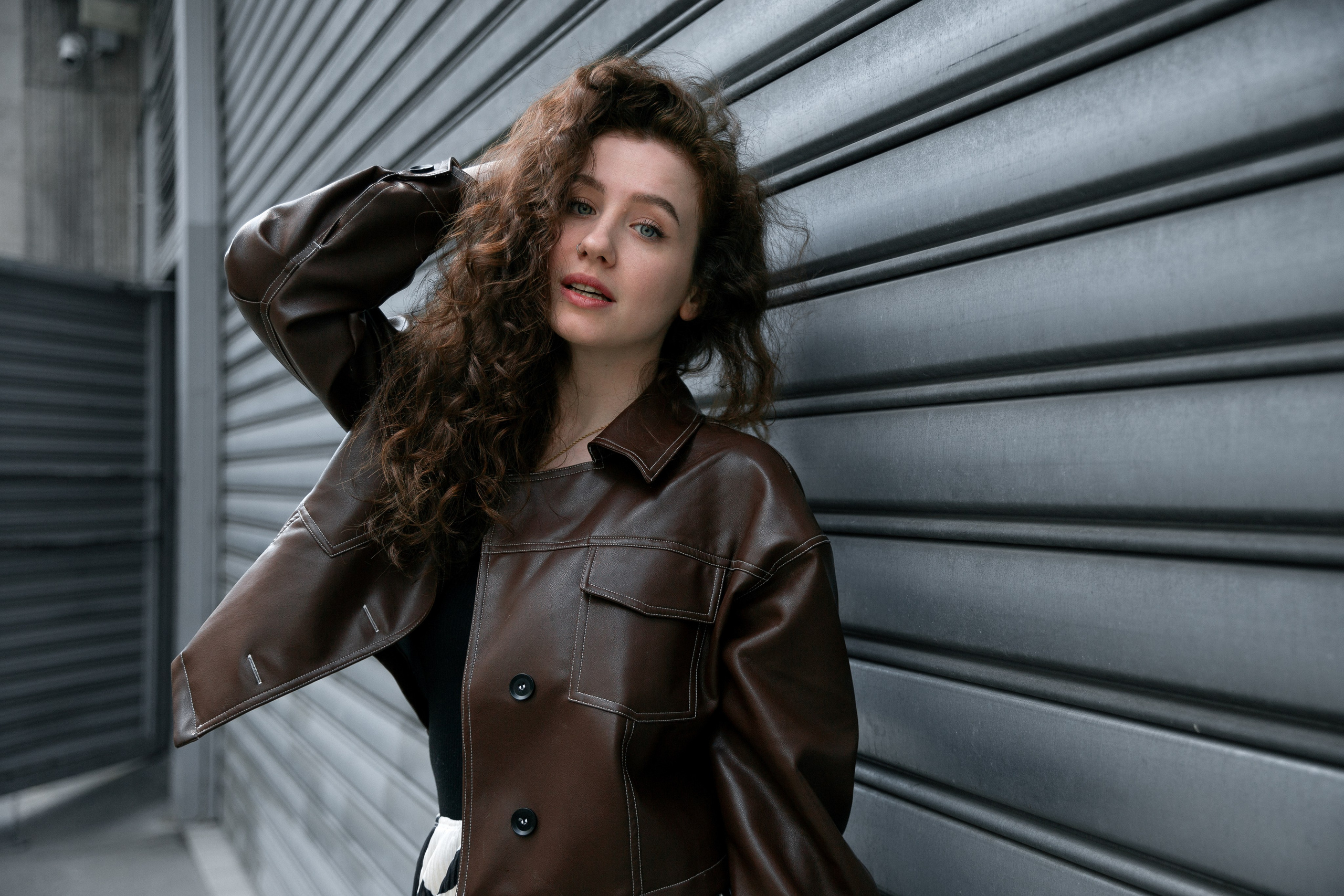 portrait photo of a girl in a black jacket against a gray wall