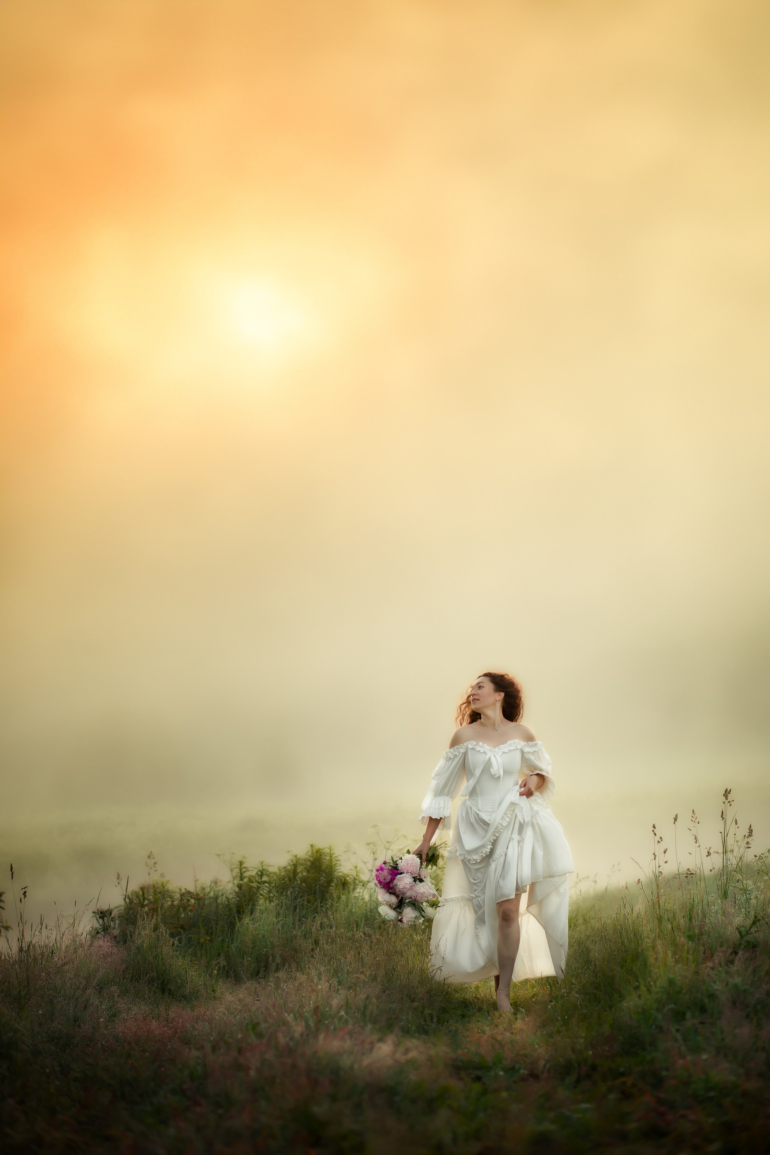 Девушка в белом платье с букетом, идет по утреннему полю, залитому мягким золотым светом.