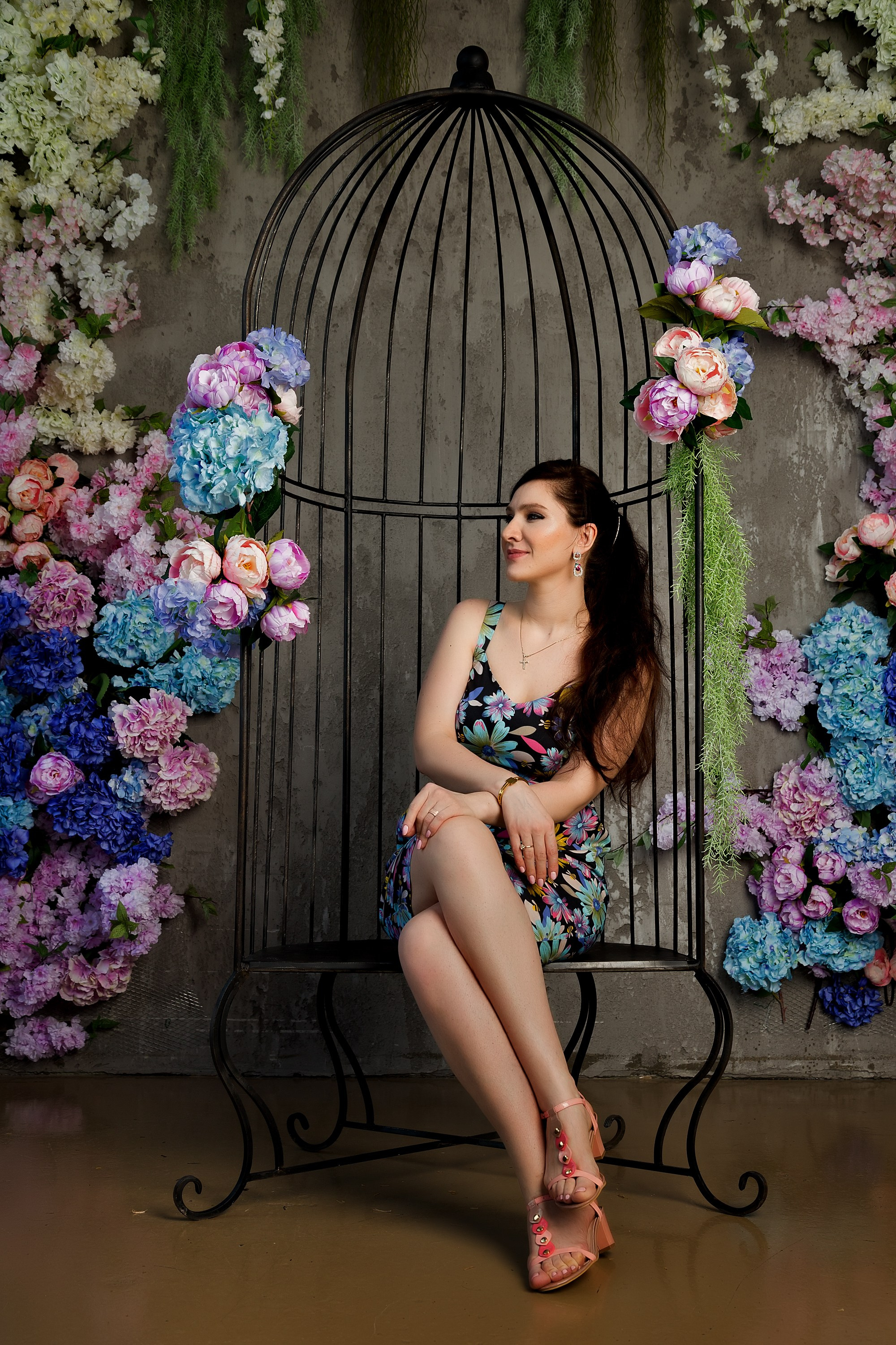 женщина среди пионов в качелях в виде птичий клетке