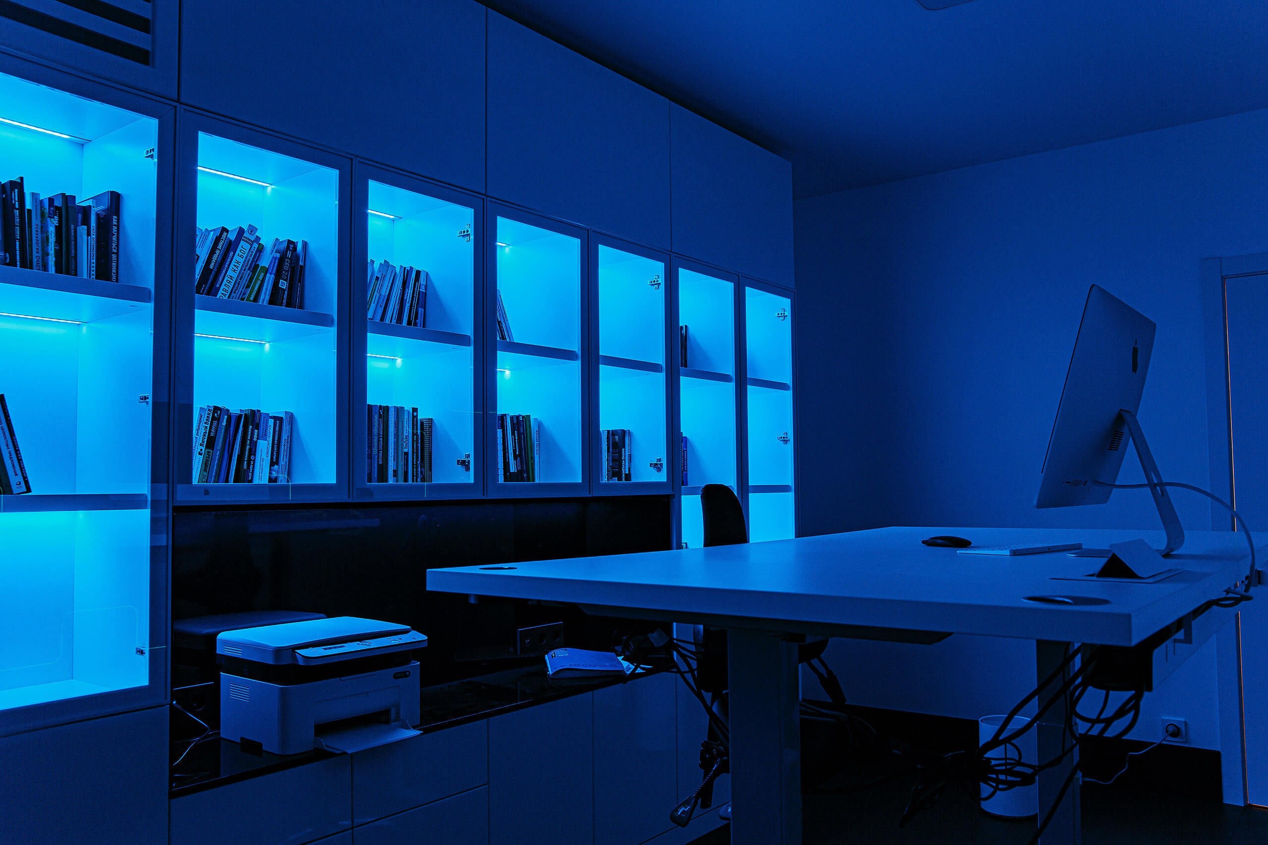 Фотография современного рабочего кабинета со встроенным шкафом и синей подсветкой полок. Снято для мебельной компании в Пензе.
