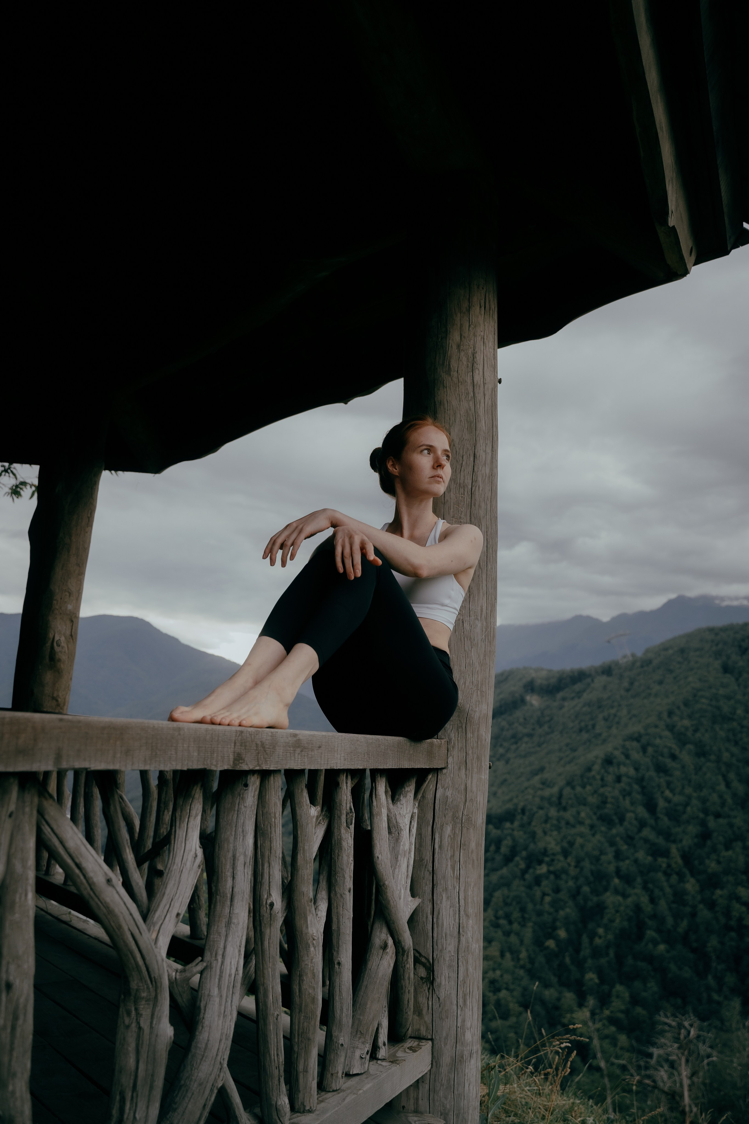 Фотоснимок сидящей девушки на заборе