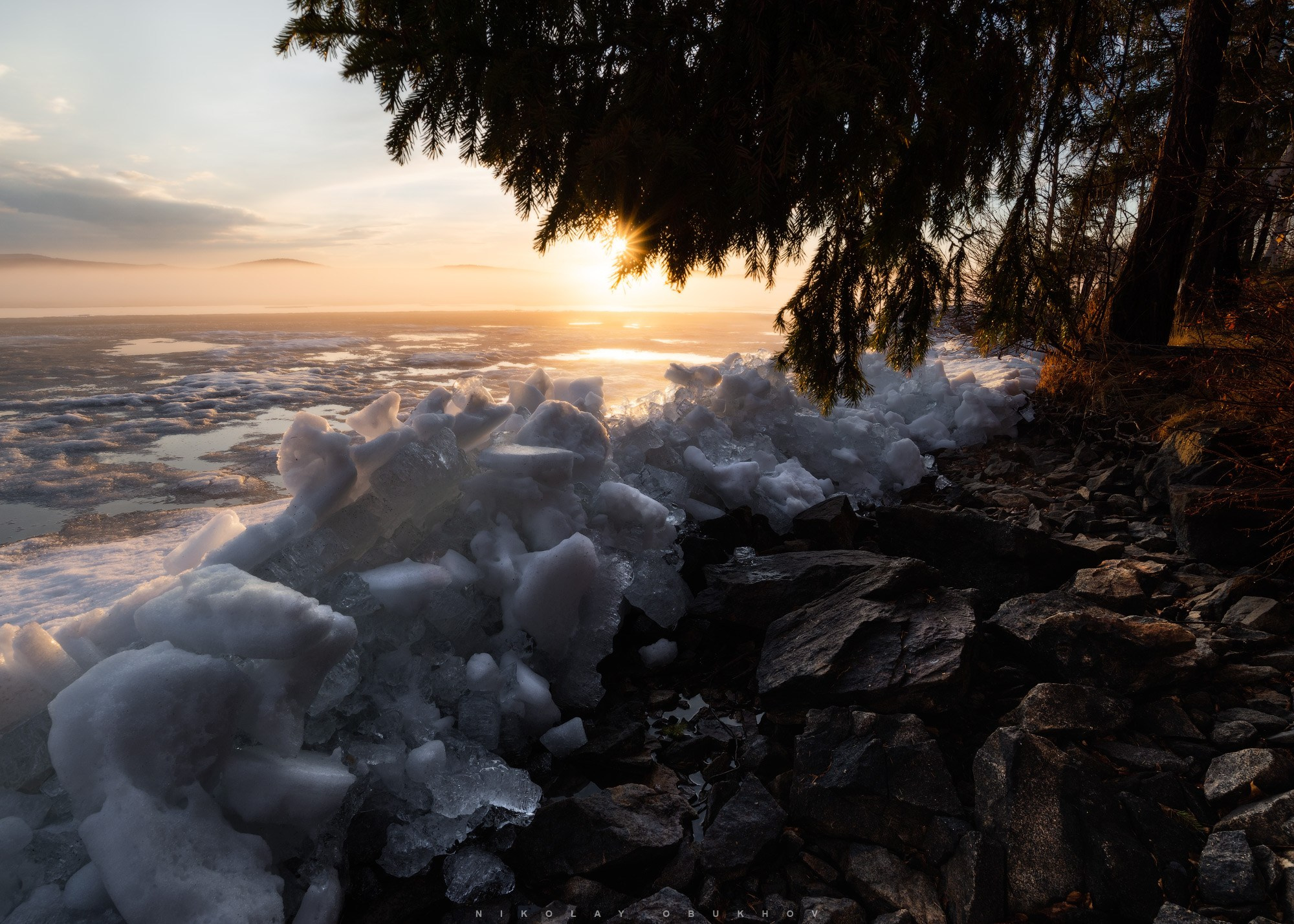 Фотографии природы Среднего Урала: последний лёд на пруду у Черноисточинска тонет в багряном свете заката, окутанный весенним туманом.