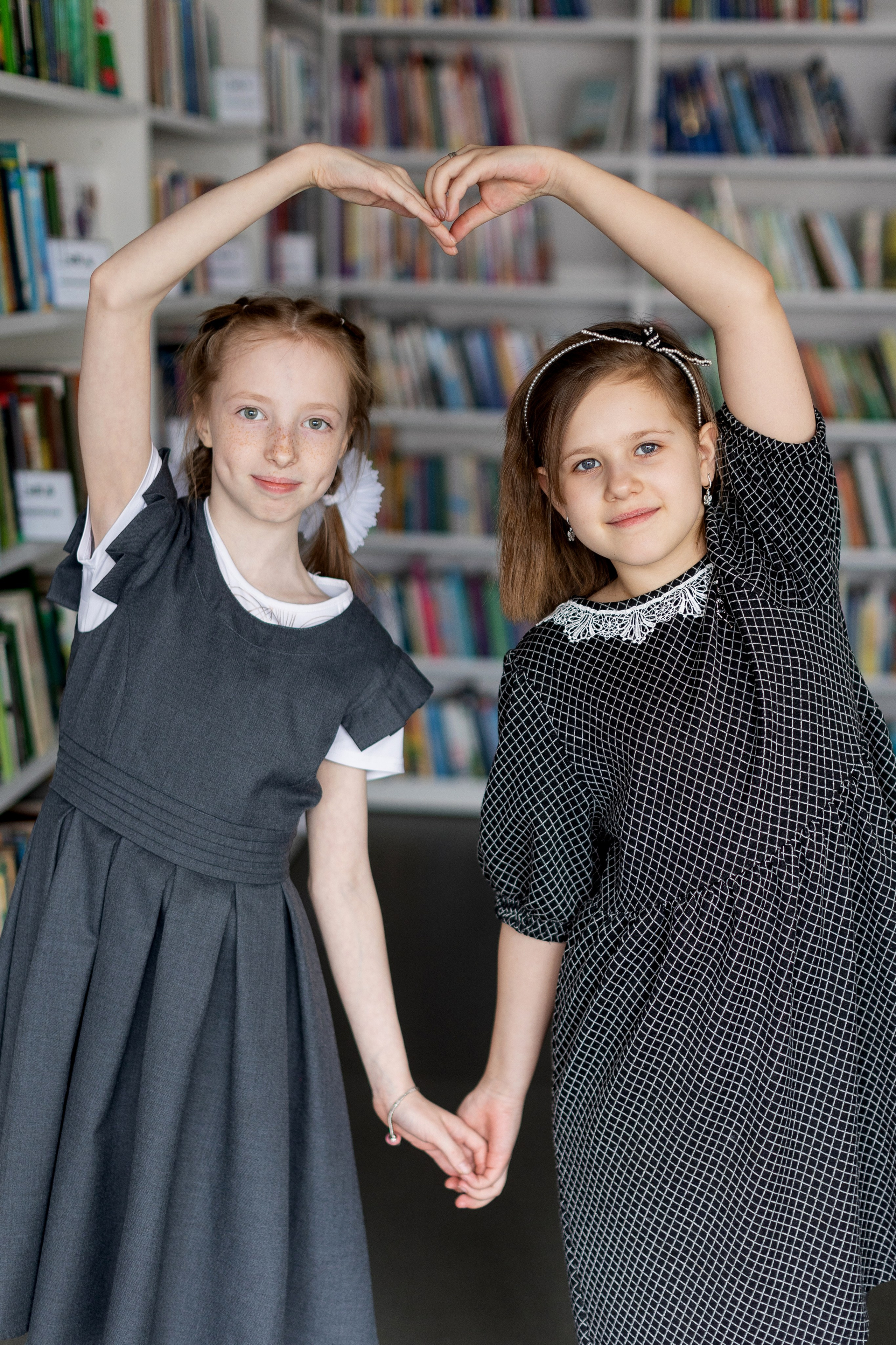 Две девочки делают сердечко из рук