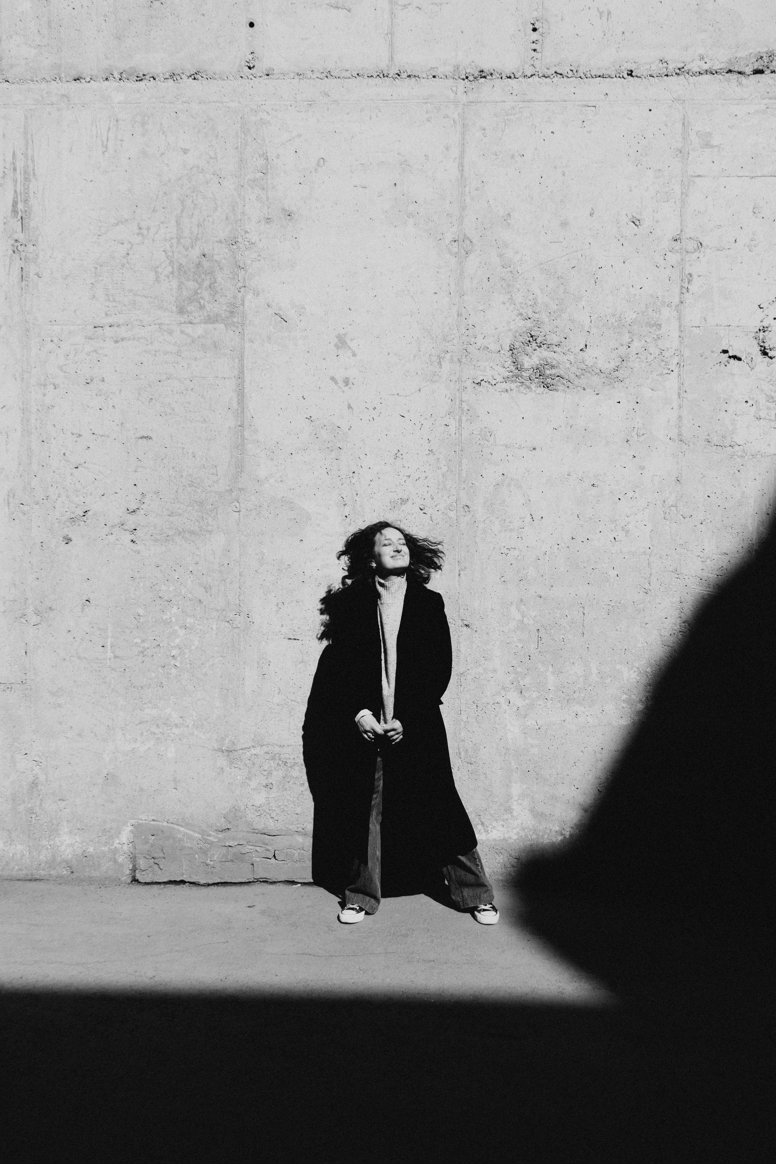 Девушка позирует на сером фоне с развевающимися волосами