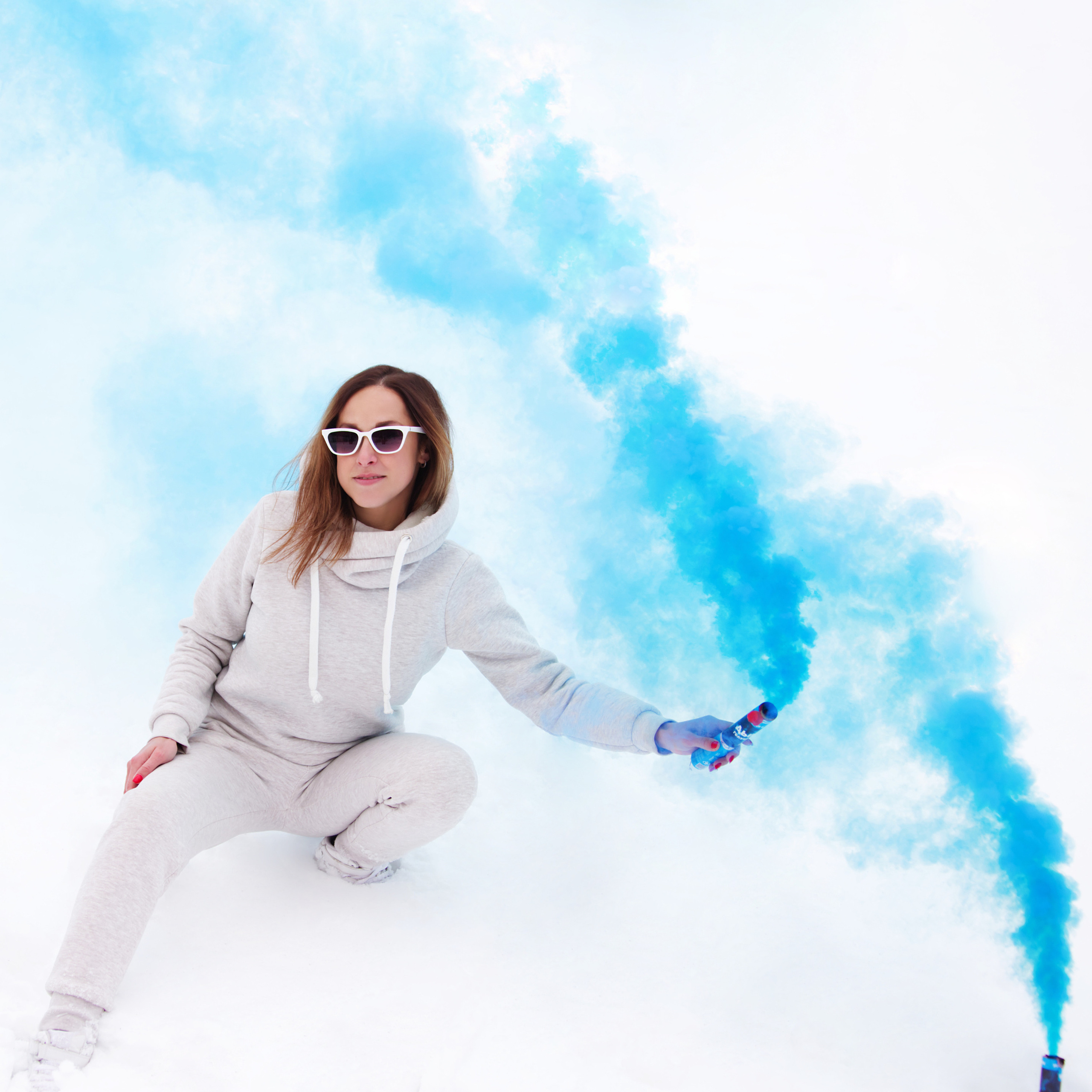 Девушка позирует с цветным дымом на снегу - зимняя фотосессия.