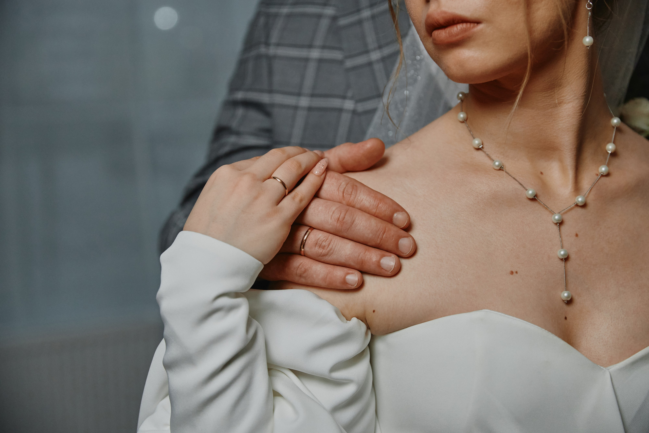 Рука жениха держит невесту за плечо