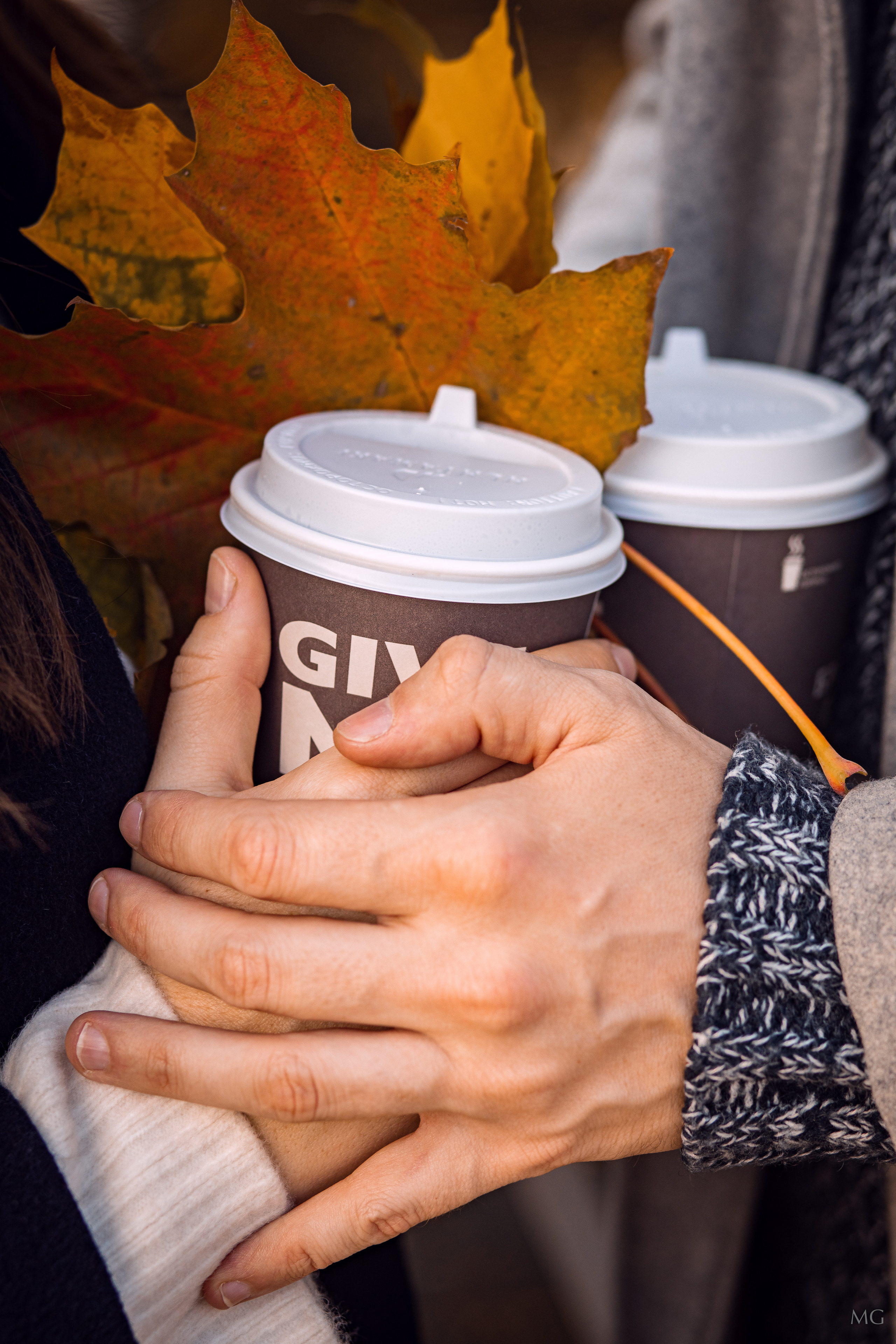 две пары рук держат одну чашку кофе осенние листья