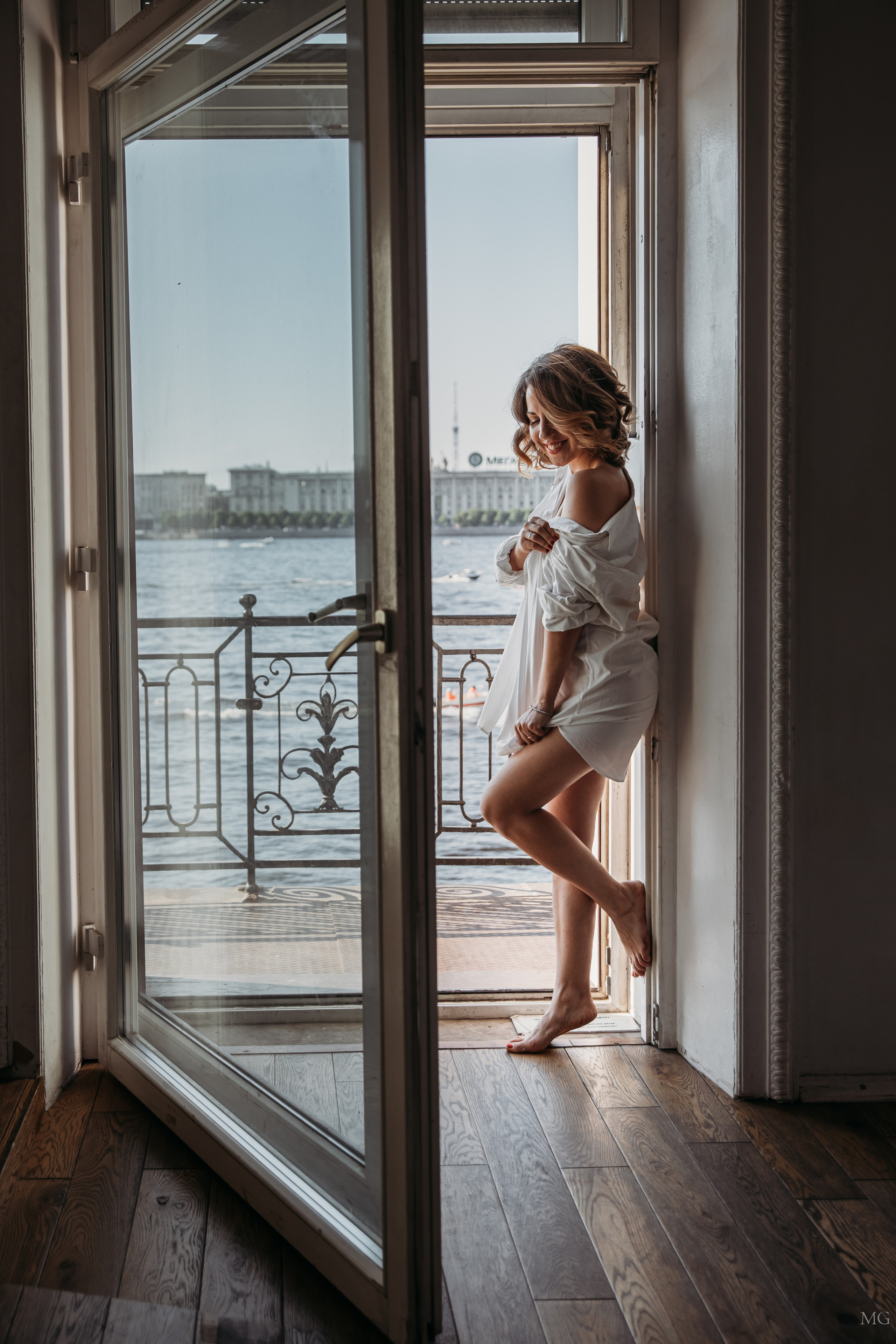 девушка в белой рубашке нежится у окна 