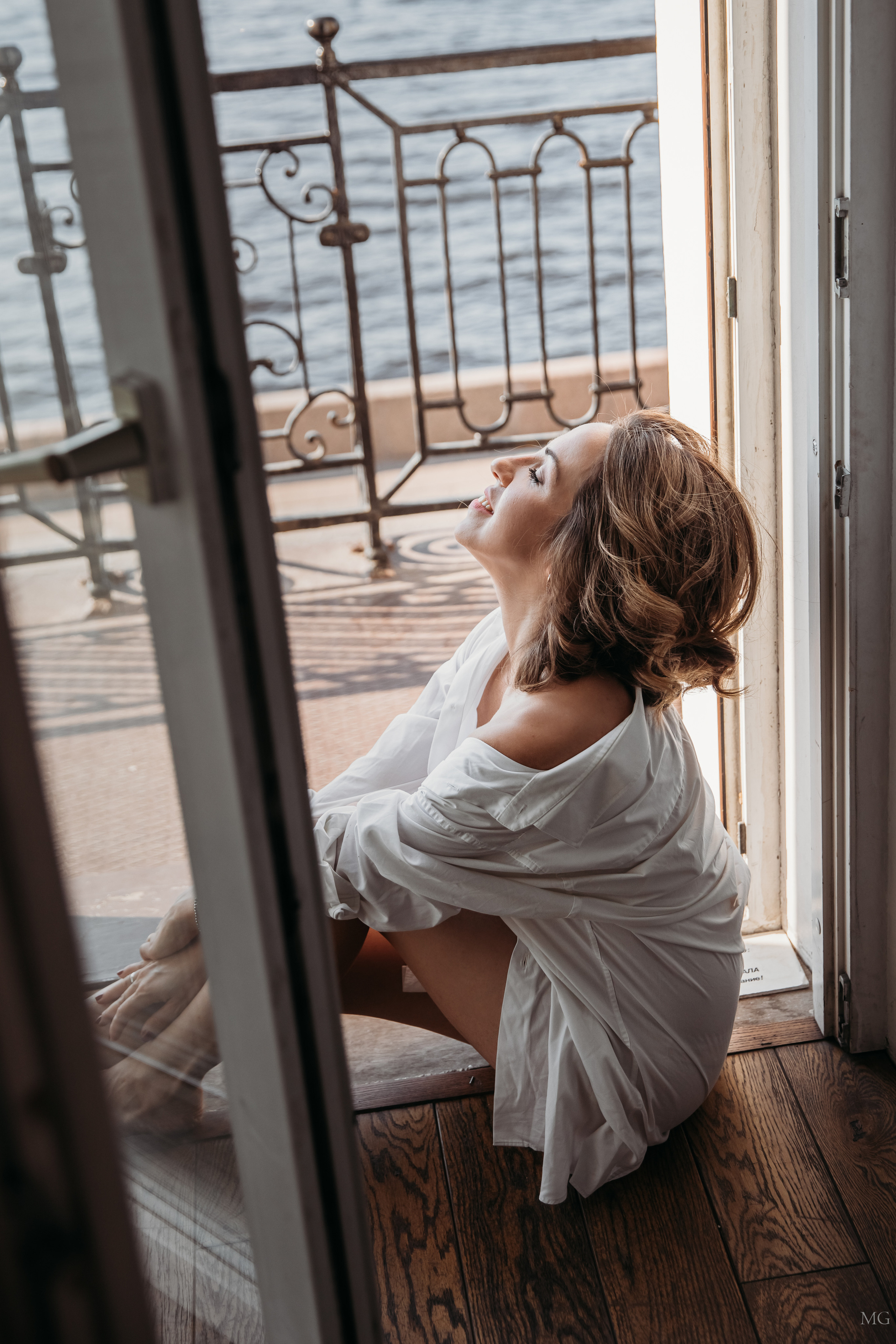 красивая девушка в белой рубашке нежится у окна 