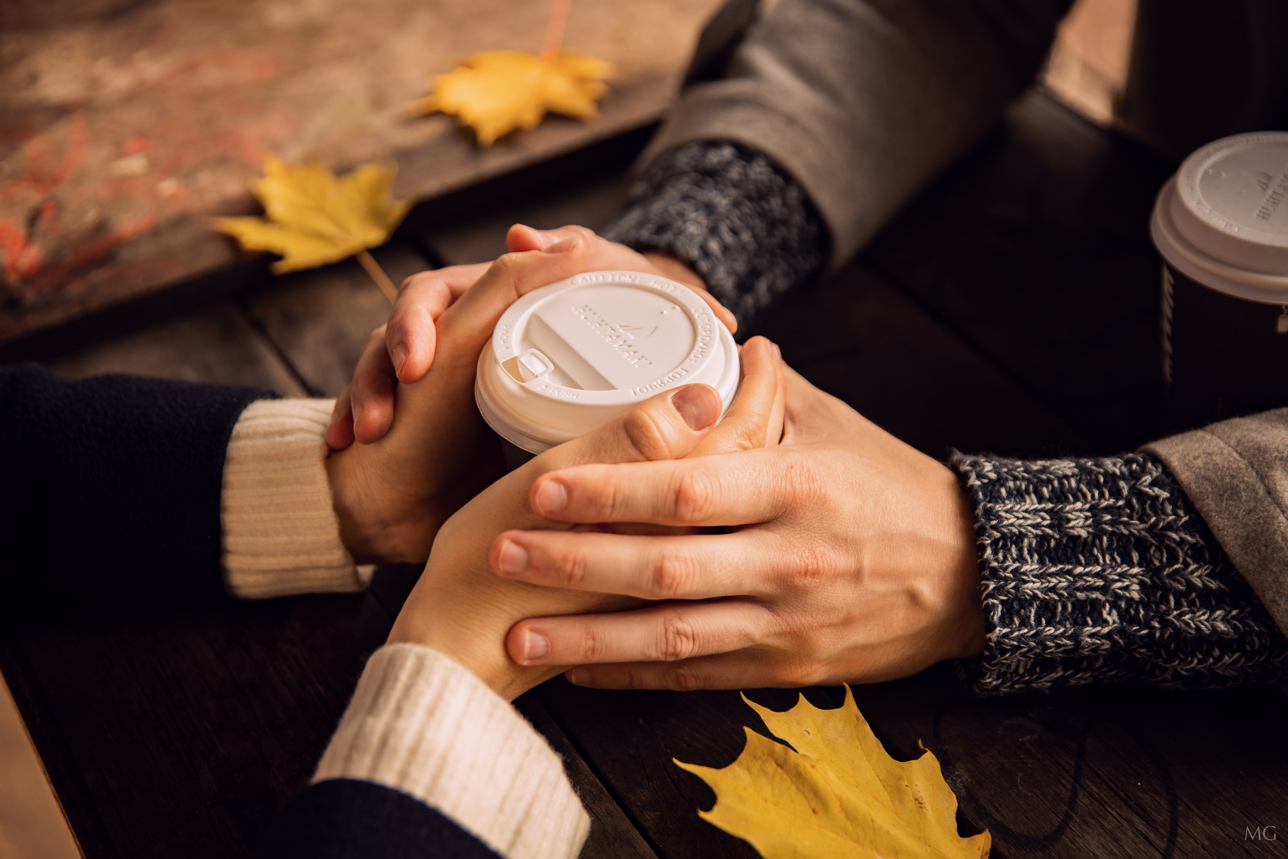 две пары рук держат одну чашку кофе осенние листья