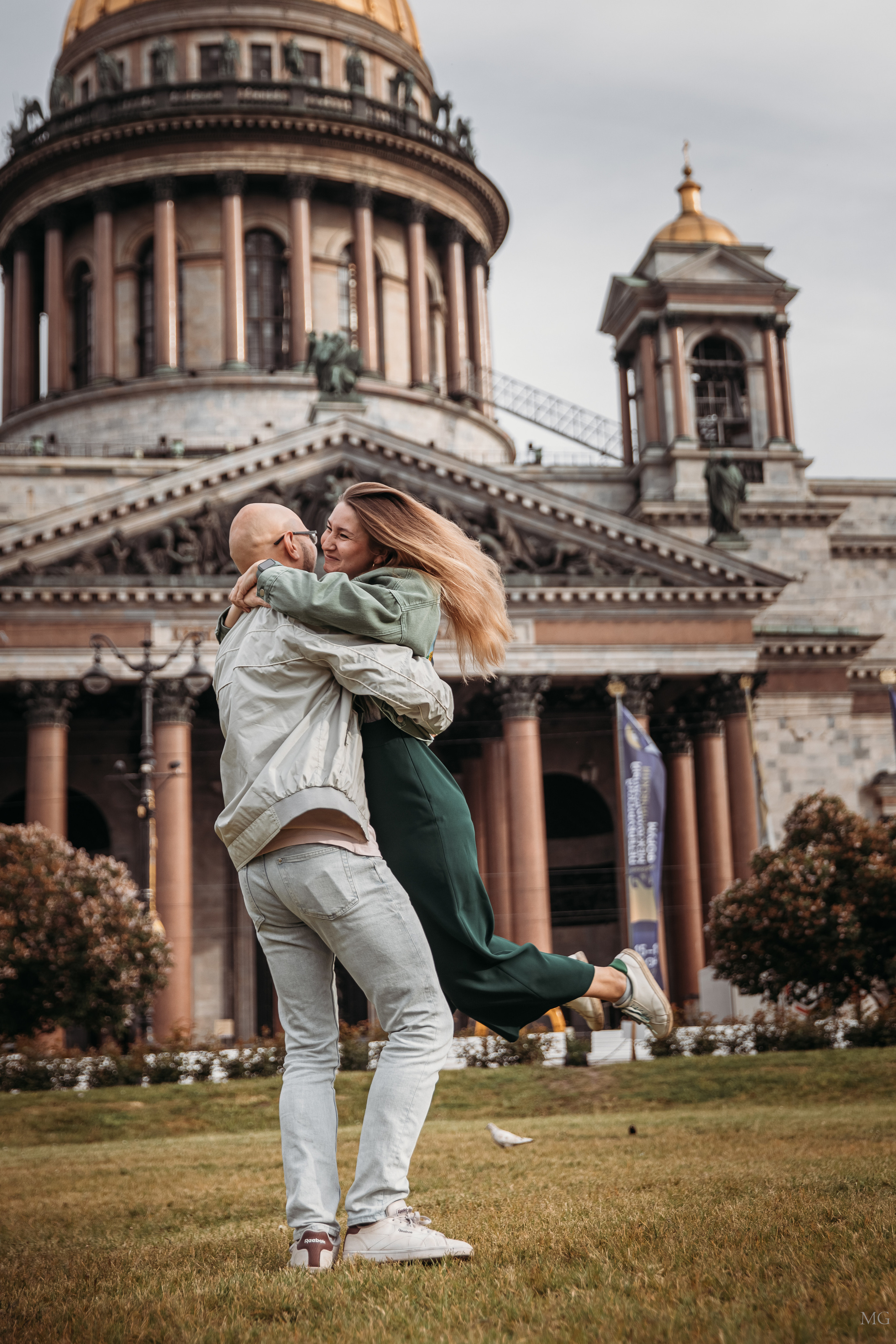 Молодой человек кружит девушку на руках у Исаакиевского собора