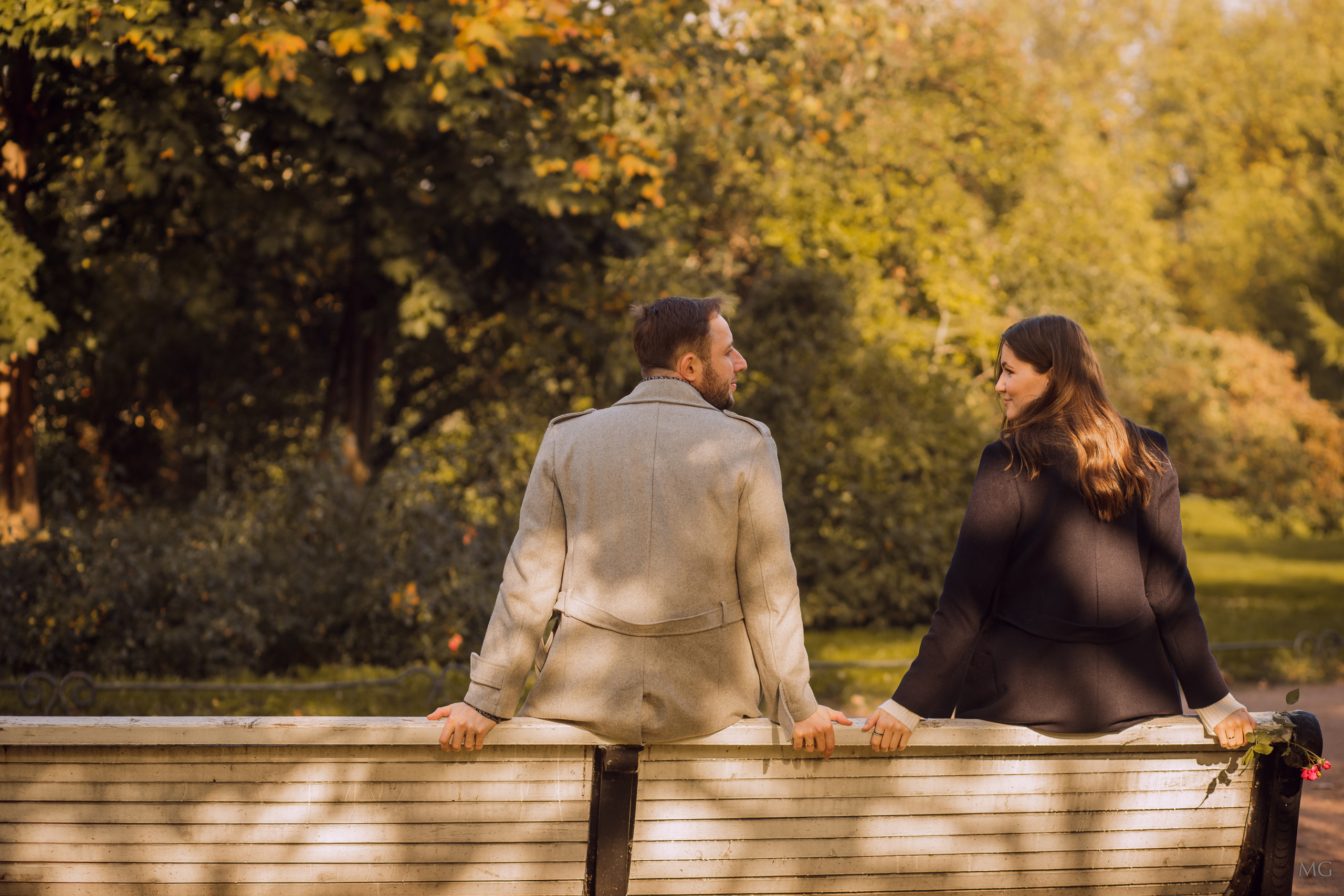 Влюбленные сидят на скамейке в осеннем парке