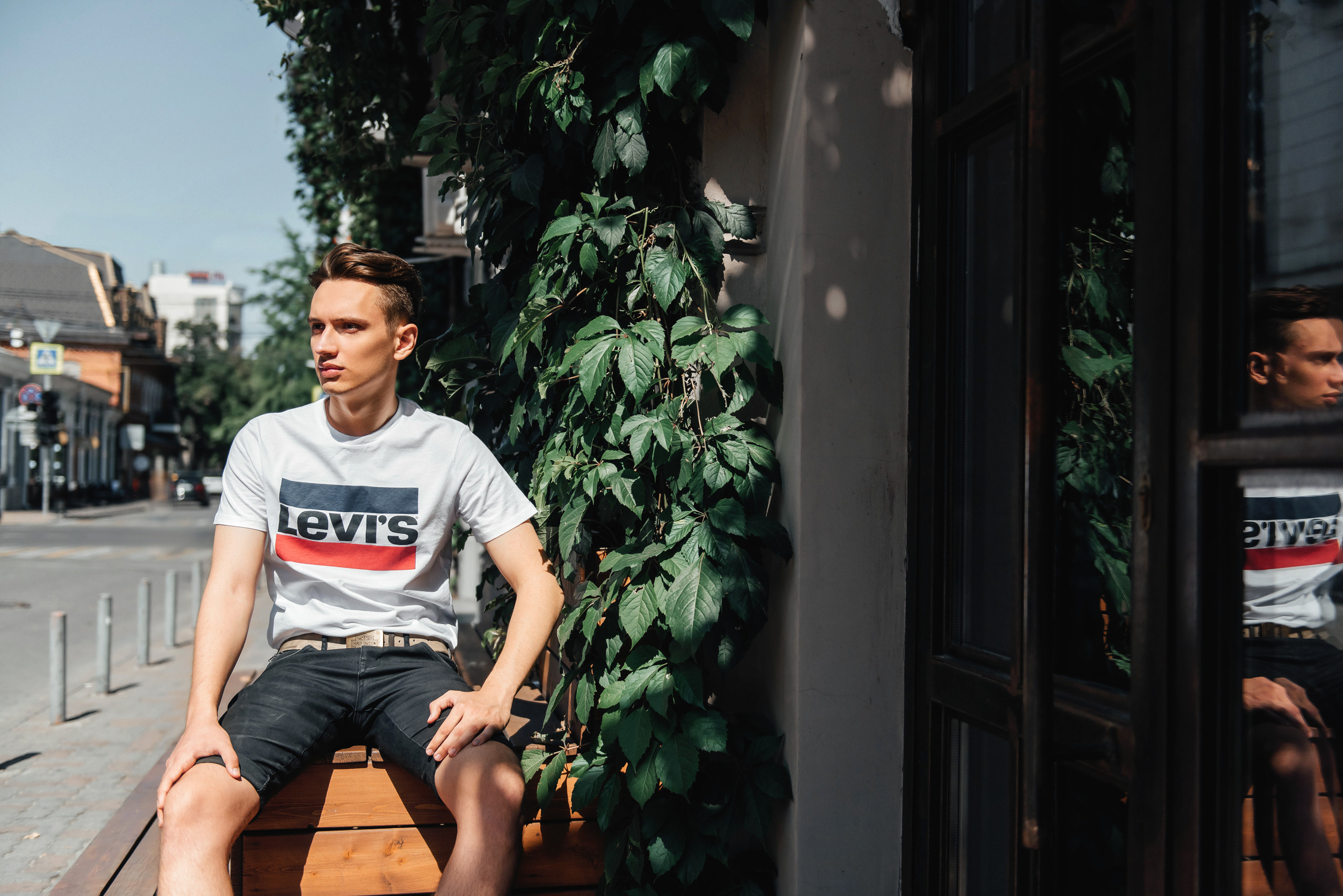 Парень сидит на скамье у кафе