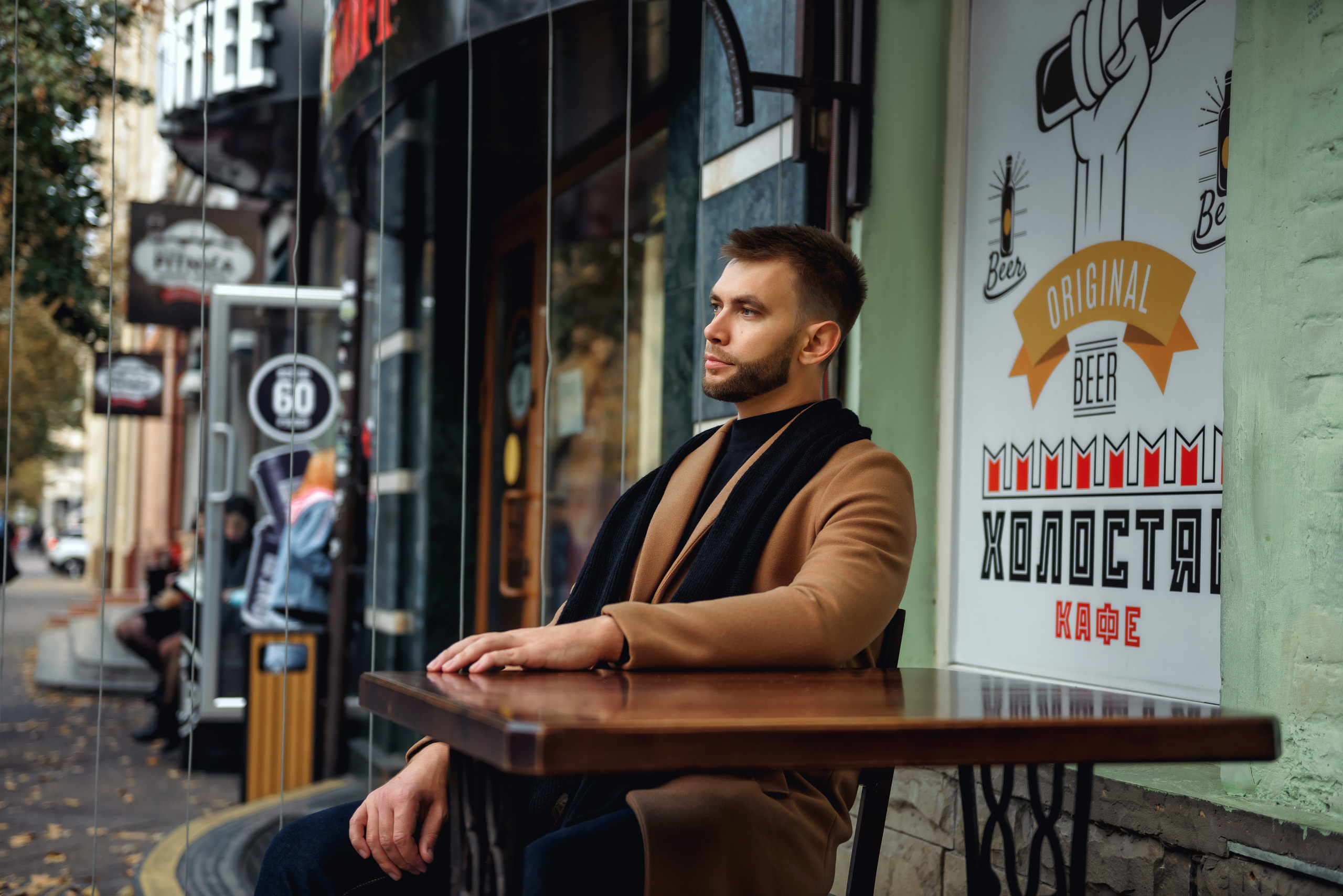 Парень сидит за столиком летнего кафе