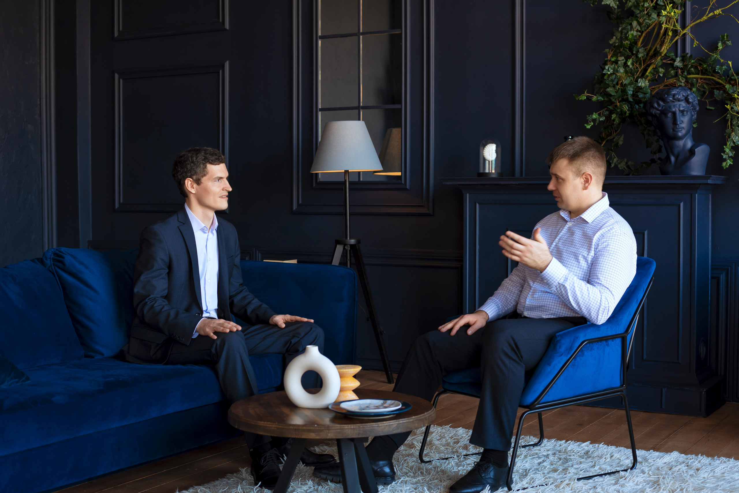 Бизнес портрет, два мужчины сидя на диванах ведут переговоры