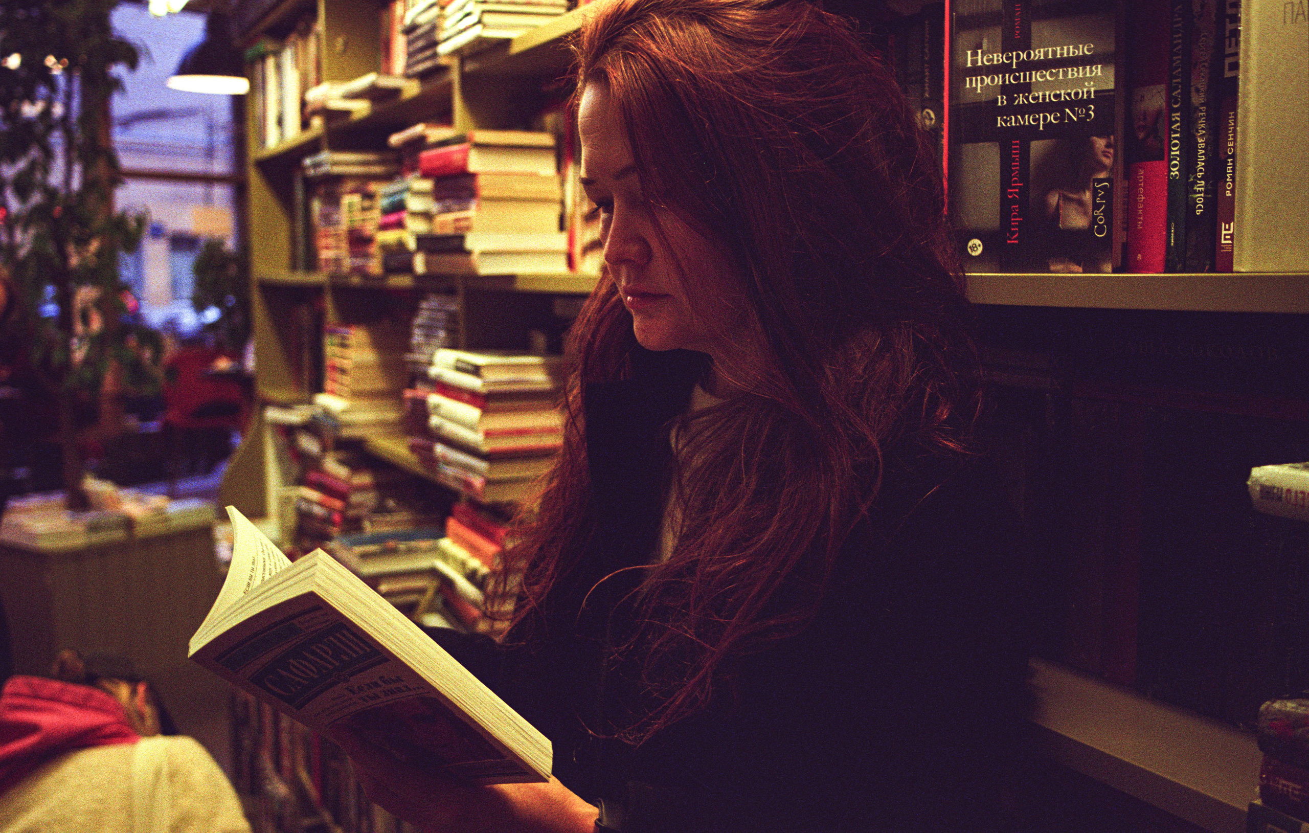 Девушка читает книгу в книжном магазине.