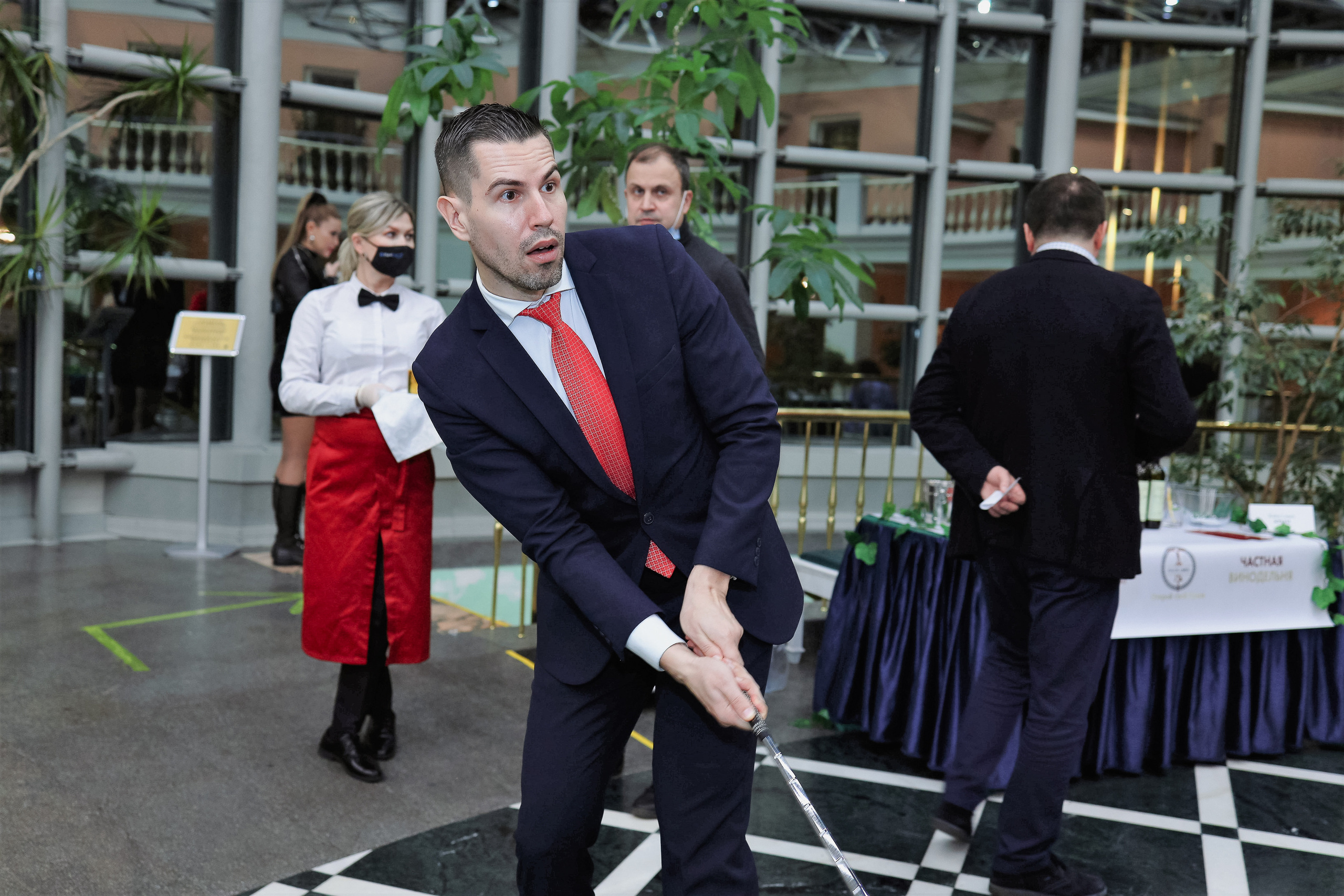 Молодой человек готовится отправить в лунку мяч, играя в мини-гольф.