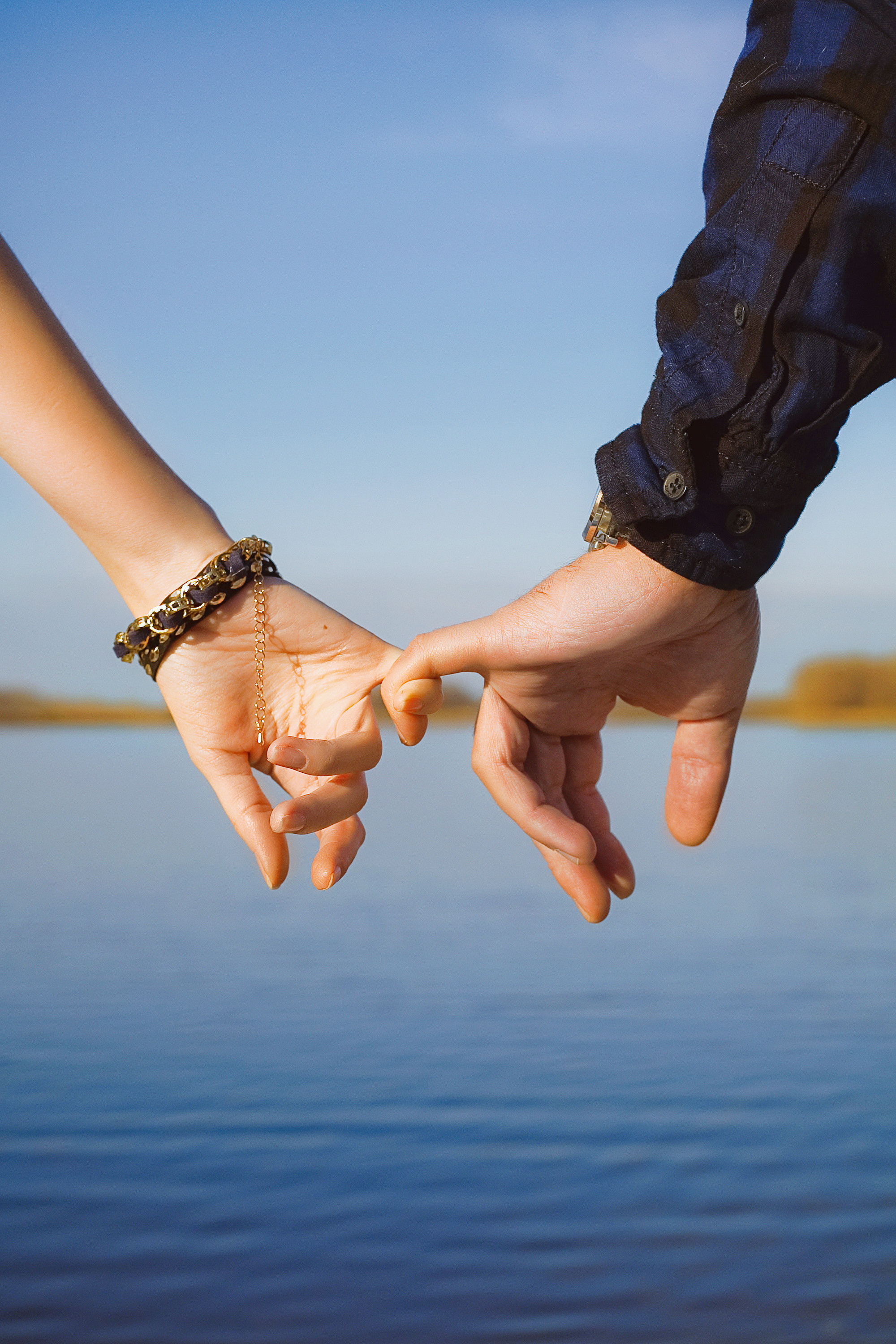 мужская рука и женская рука на фоне озера