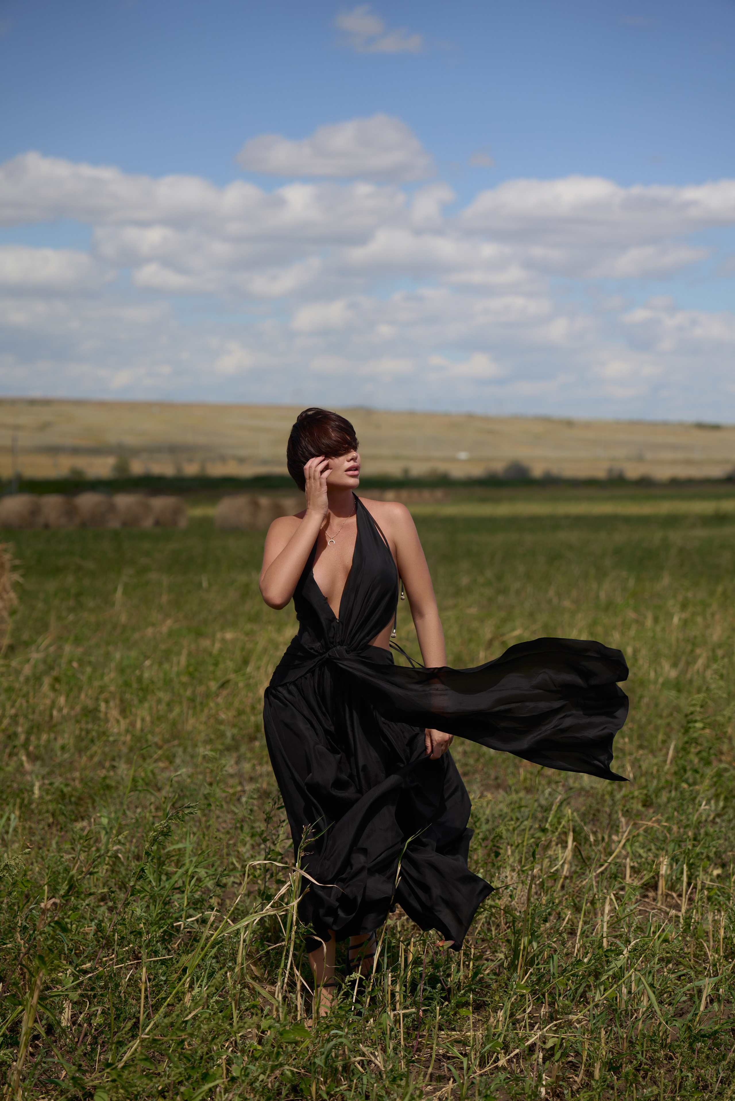 На этом фото с прогулочной фотосессии прекрасная девушка в развевающемся черном платье. Снято в полях Саратова со стогами сена. Фотограф Саратов - Москва