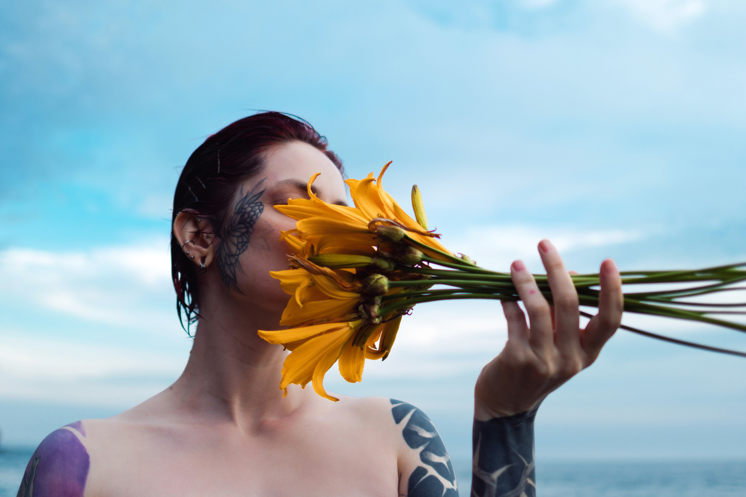 Ню фотосессия во Владивостоке. Обнаженная девушка с букетом желтых цветов, закрыла лицо цветком. Крупный план