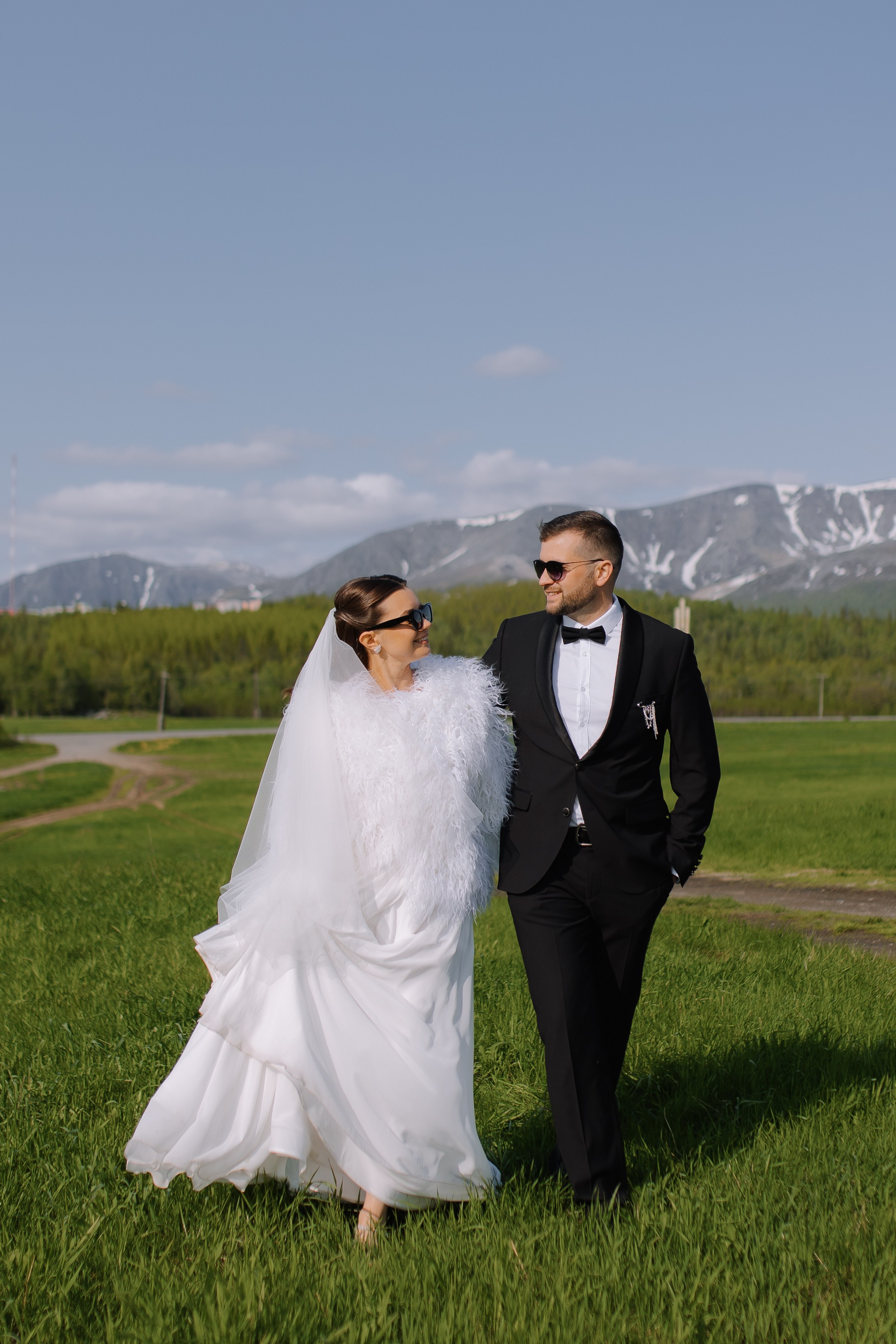 Жених и невеста уверенно идут рука об руку по центральной улице Кировска.