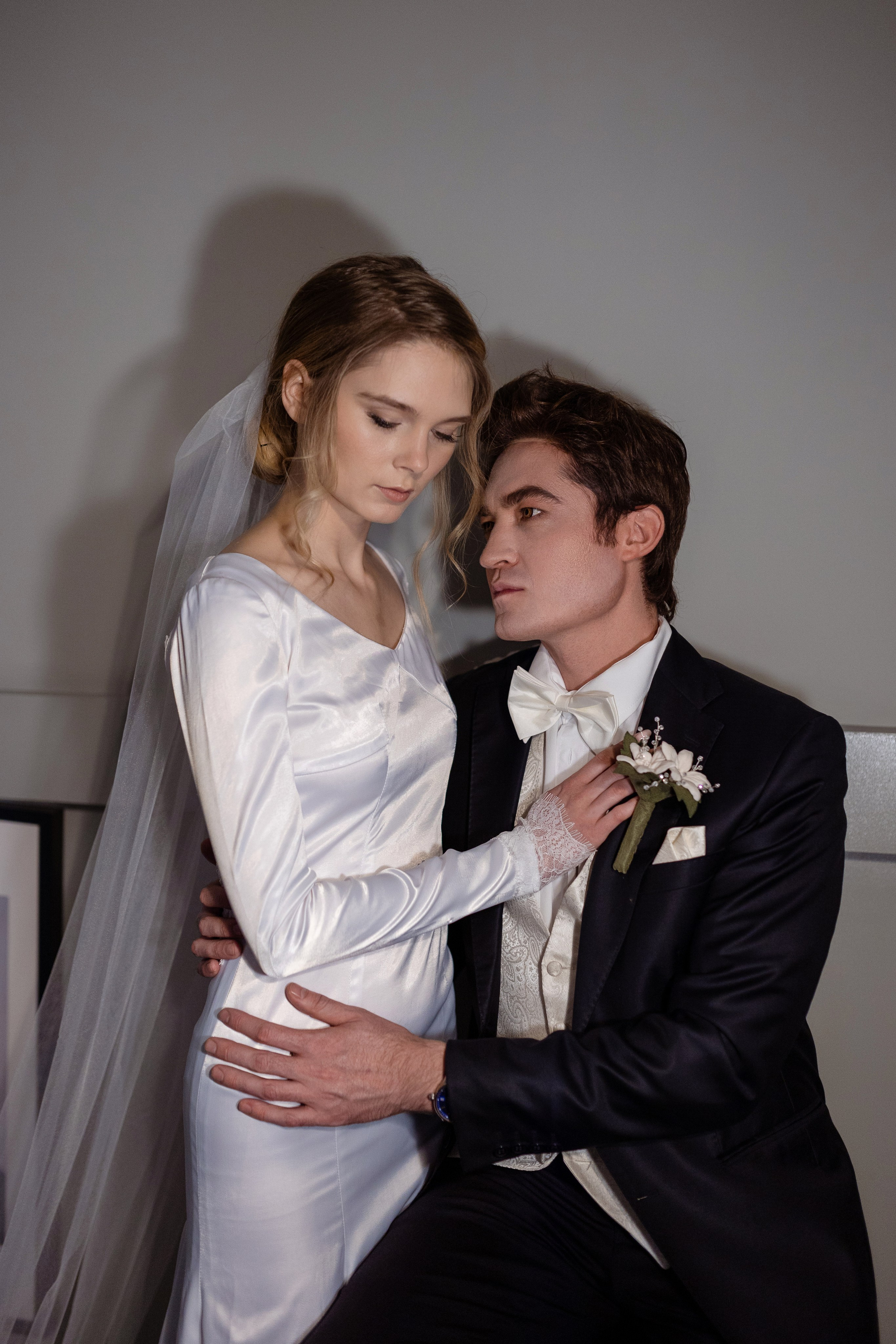 Сидящий жених обнимает рядом стоящую с ним невесту