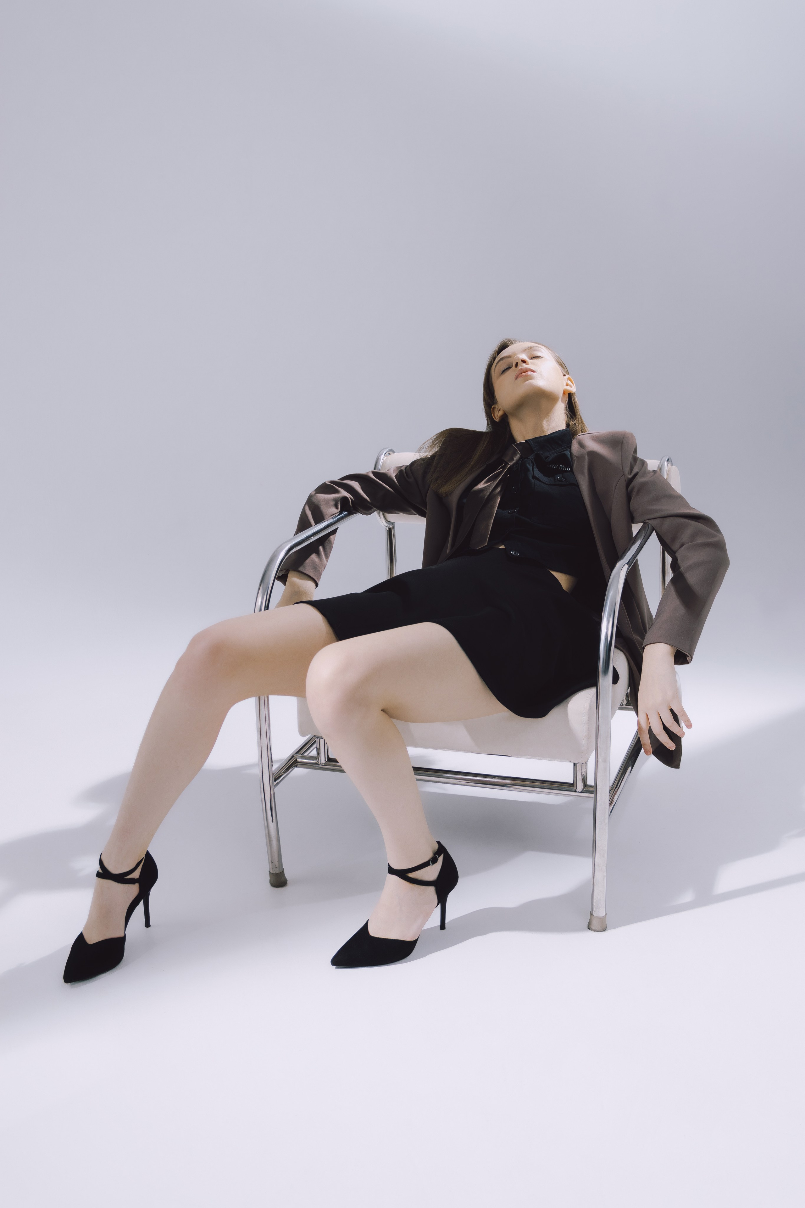 Элегантная поза модели в чёрном платье и туфлях на каблуке — идеальный пример студийной фотосессии.