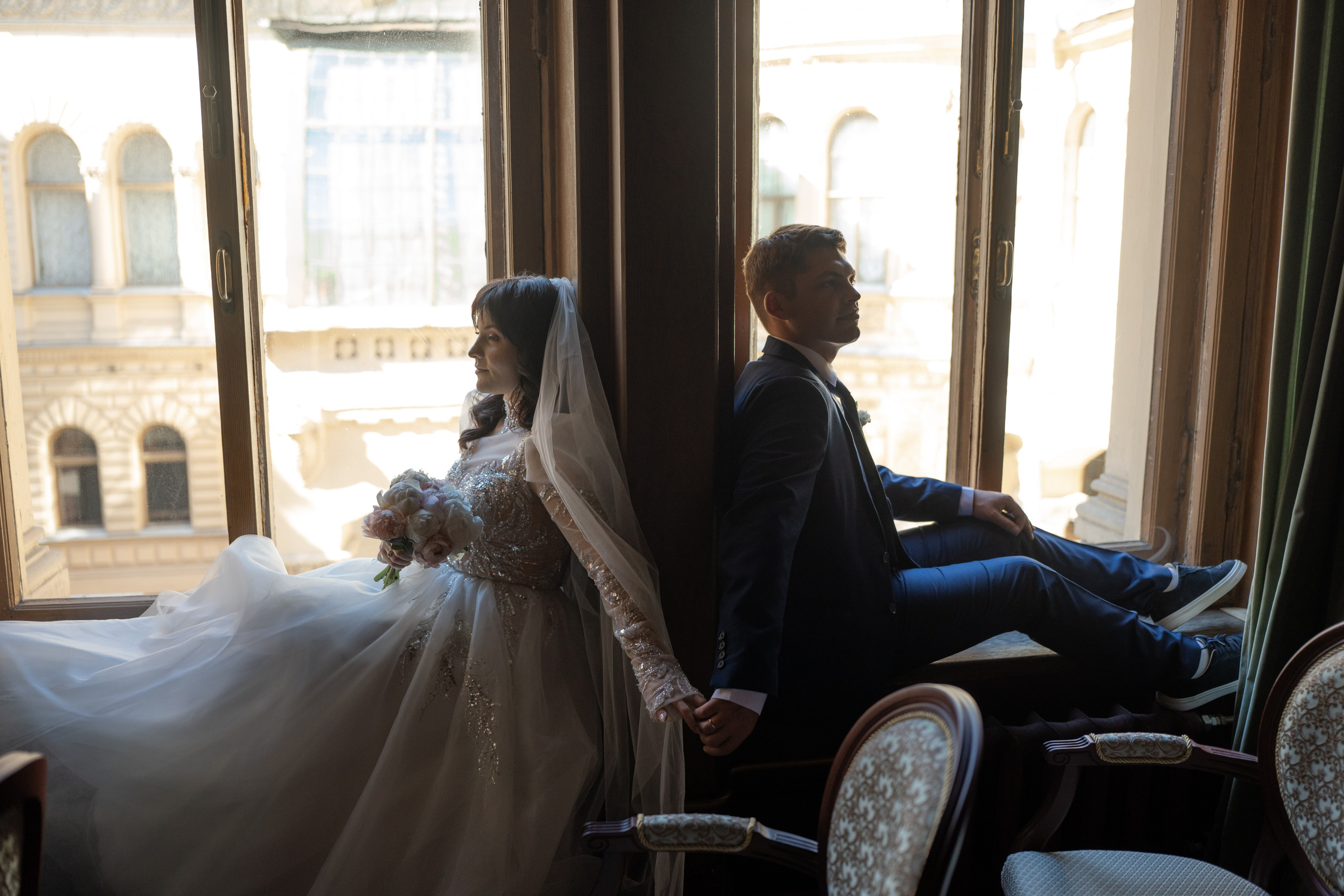 Свадебная фотосессия в Доме ученых, Дворце князя Владимира в Санкт-Петербурге. Жених с невестой в дубовом зале сидят на подоконнике у окон.