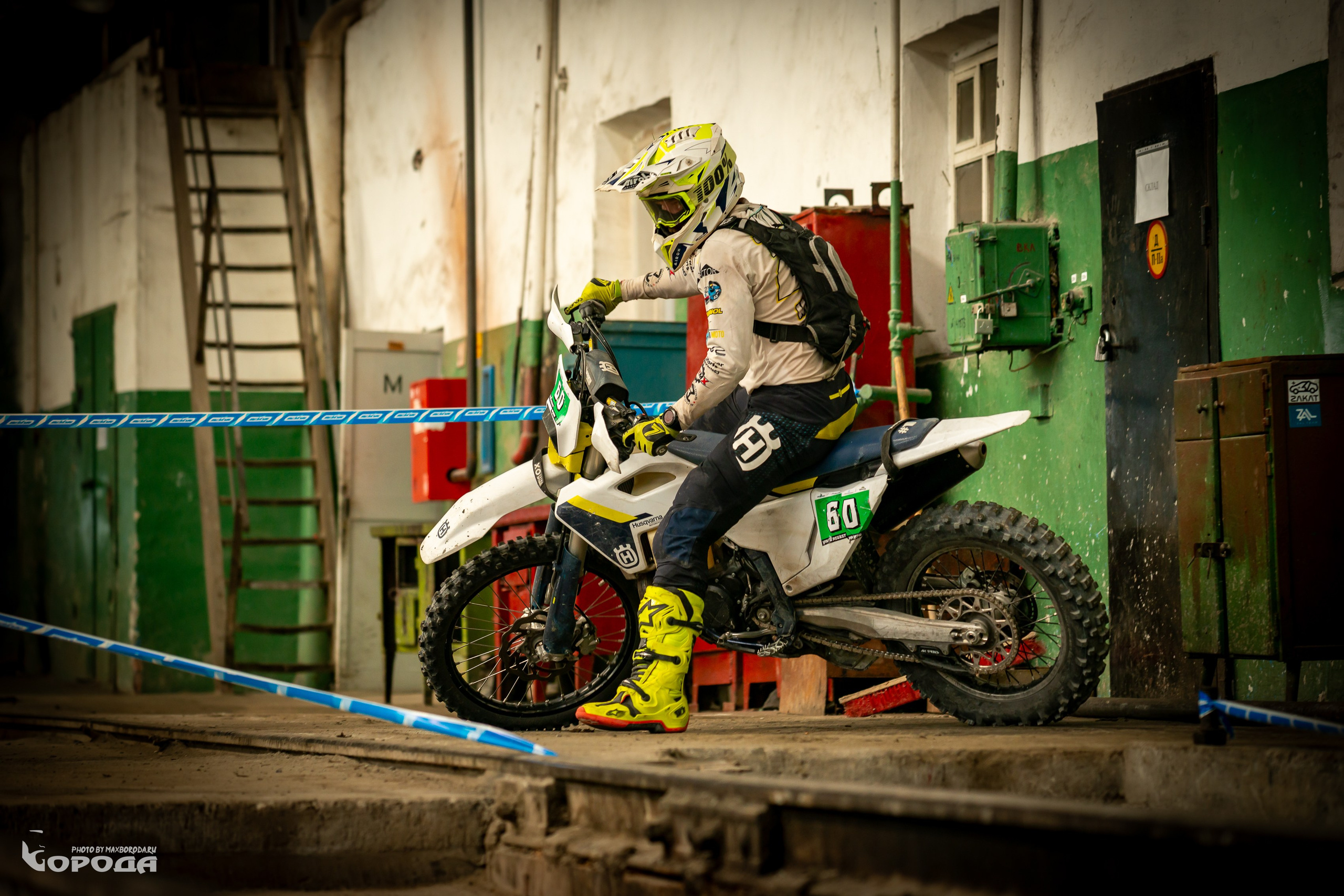 Мотоциклист в экипировке на Husqvarna FC450, в индустриальном антураже.