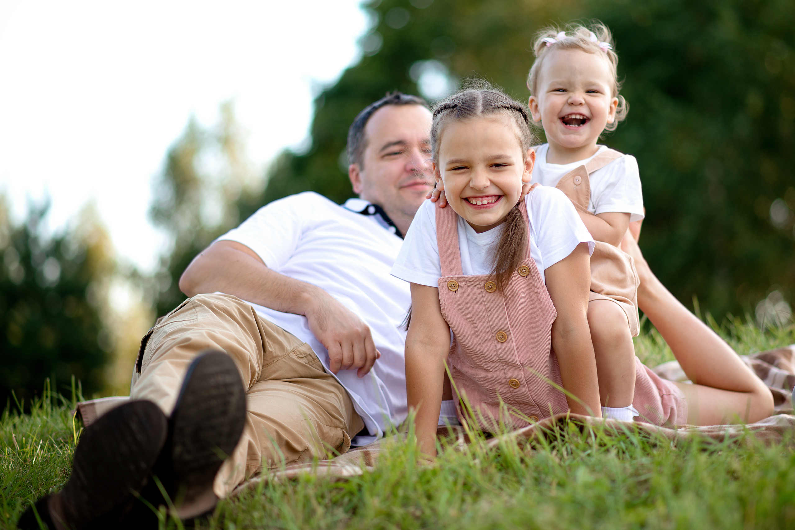 Семья папа и две дочки сидят на природе