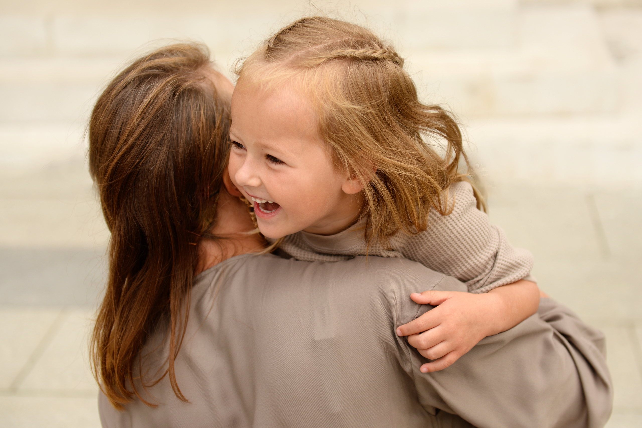 Мама обнимает смеющуюся дочку