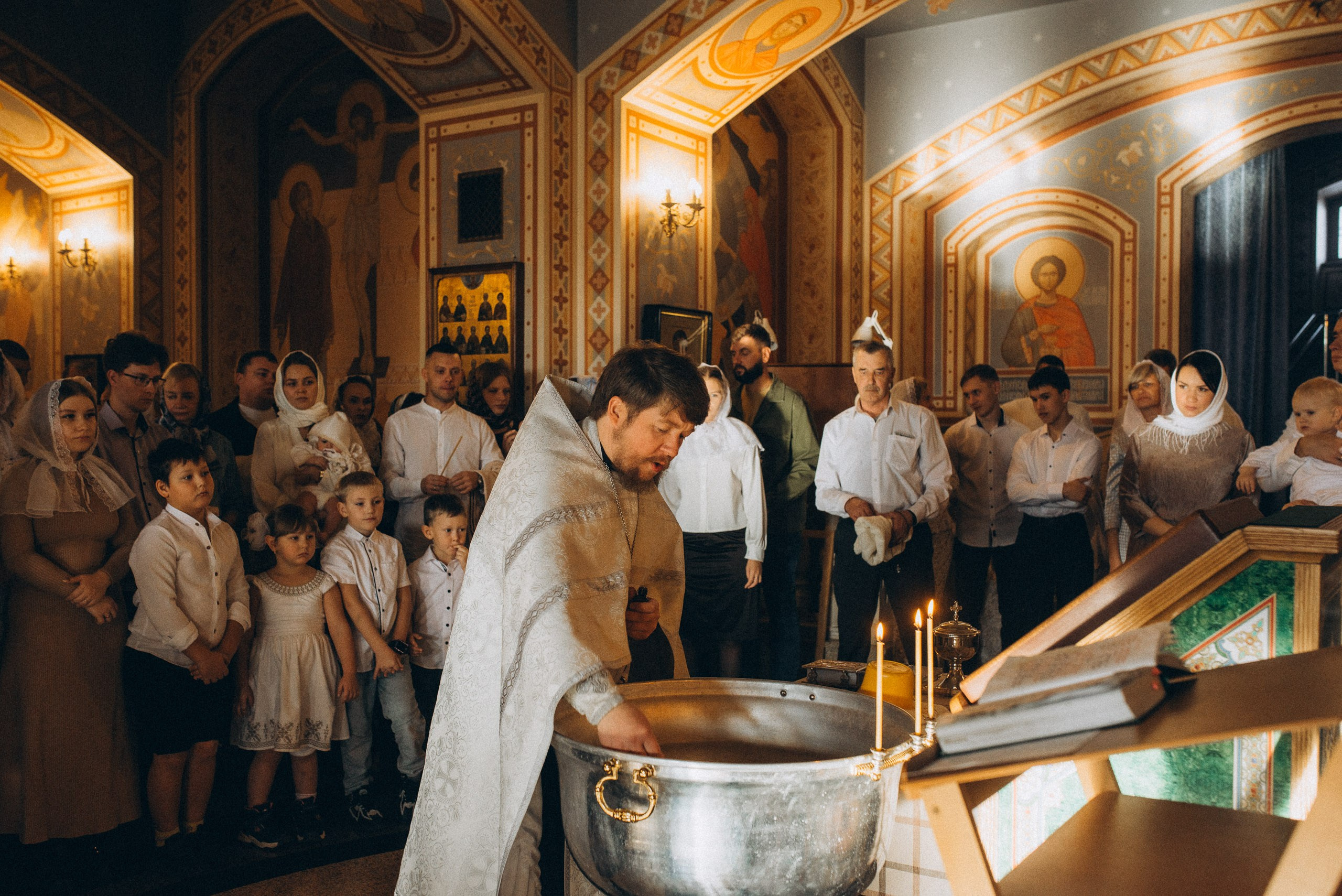 Репортажная съемка крещения — священнослужитель у купели и гости в церкви, Новосибирск