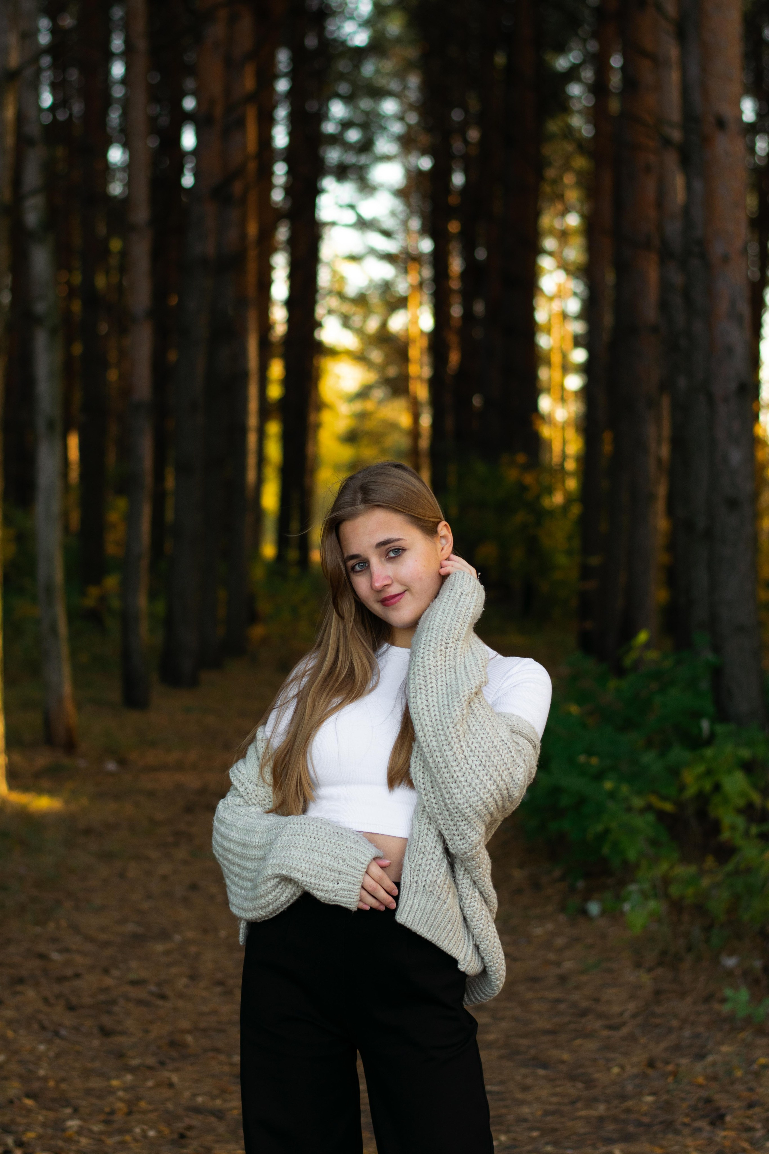 Девушка позирует в сосновом лесу в белой футболке