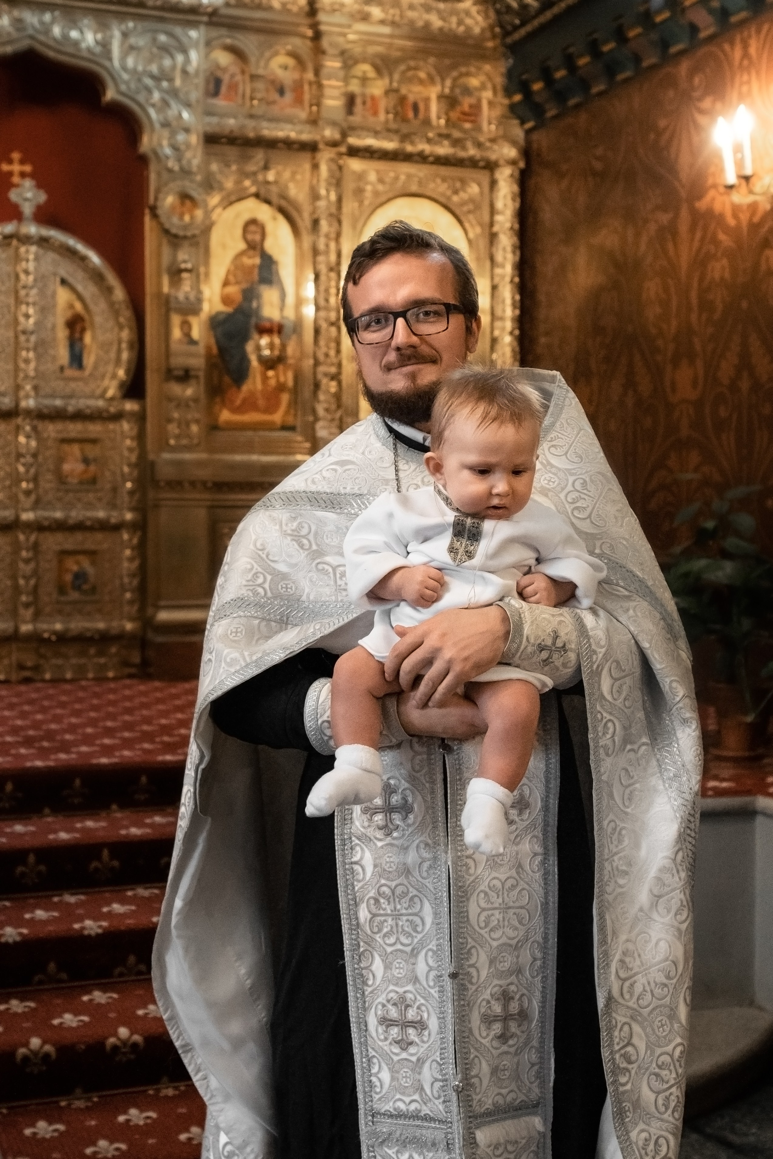 портрет священника с малышом после крещения в Оптинском подворье Санкт-Петербурга
