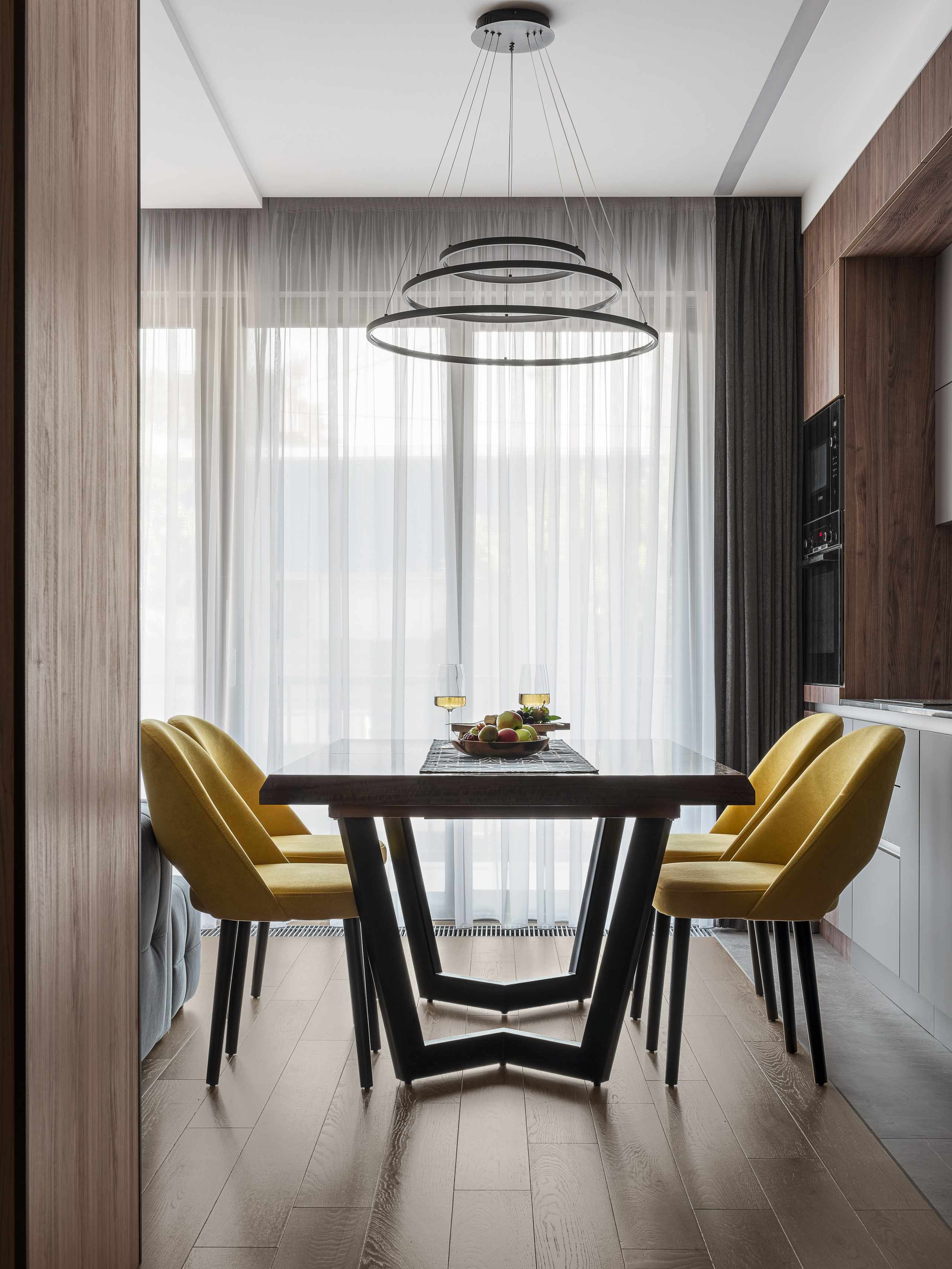 Современная столовая зона с обеденным столом, желтыми креслами и дизайнерским светильником-кольцом, интерьер от Алёны Поповой и Анастасии Дмитриевой, фото Сергея Денисенко.