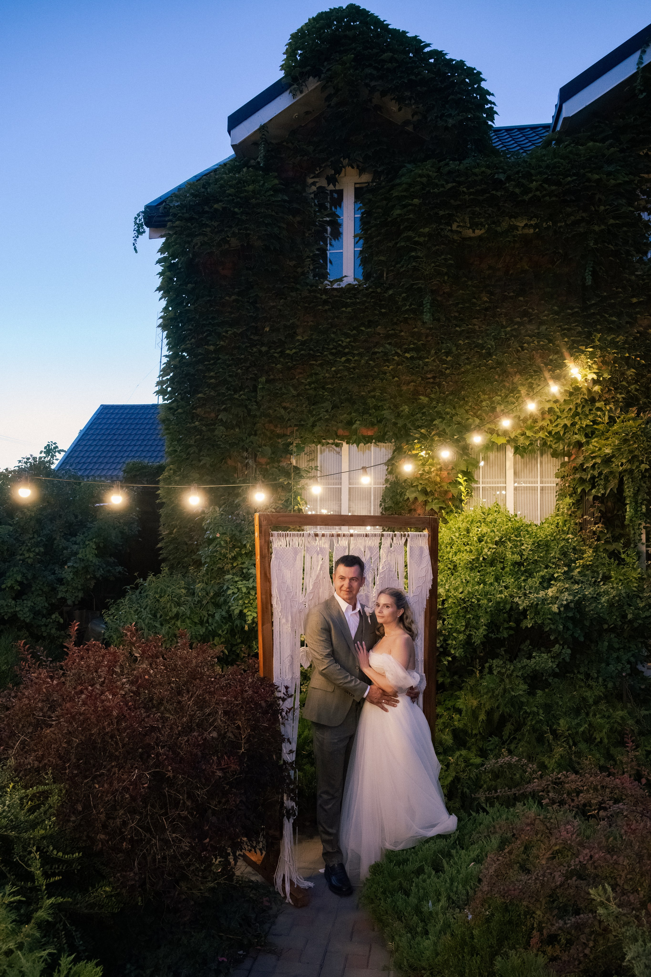 Романтическая свадебная фотосессия в Ростове-на-Дону: жених и невеста стоят на закате на фоне сада и архитектуры 