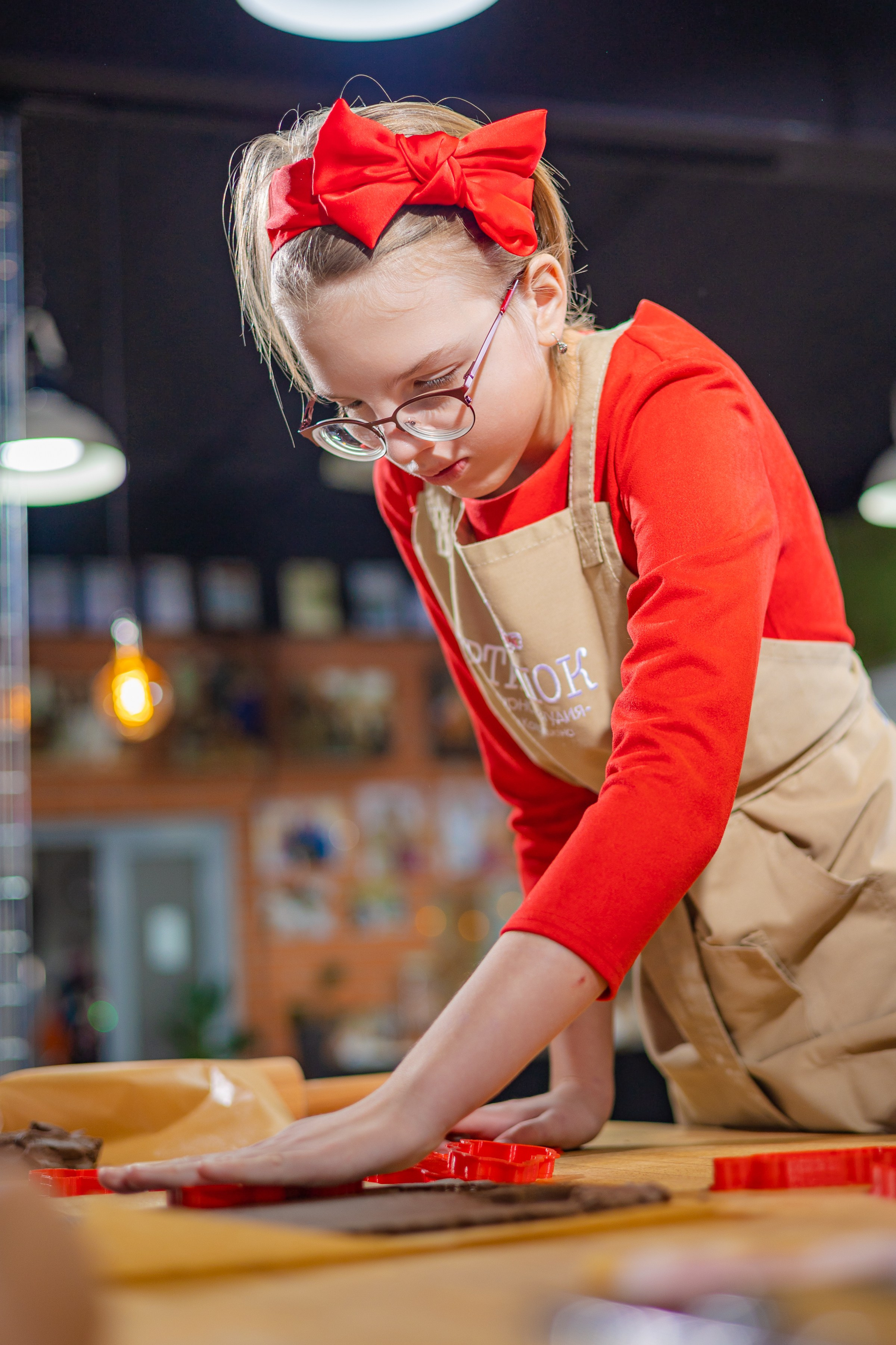 Кулинарная студия артишок девушка девочка делает печенье из тесто формочки ярко красный бант