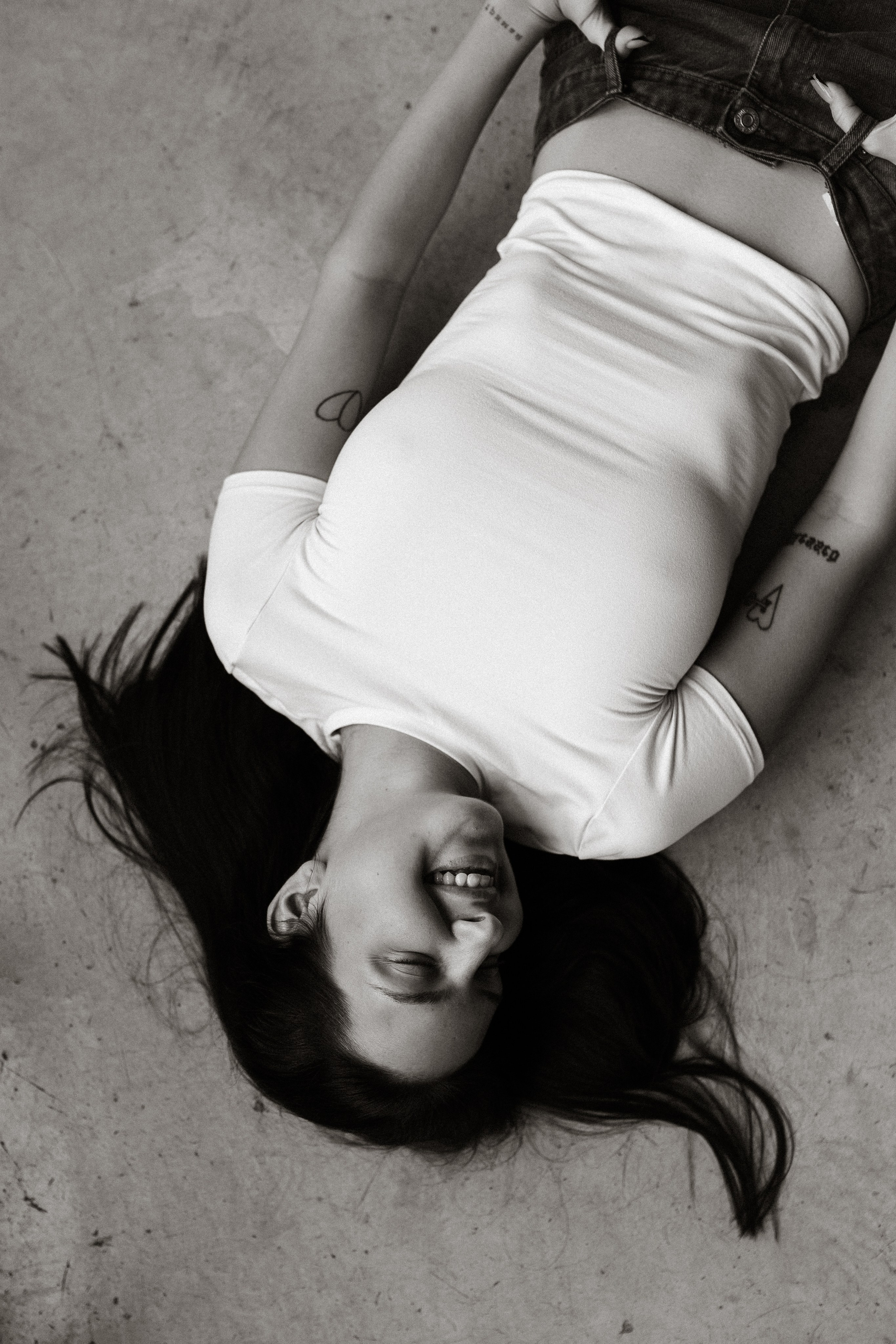 Чёрно-белый портрет модели в белой футболке и джинсах, позирующей лёжа на полу, стильная студийная фотосессия в Санкт-Петербурге