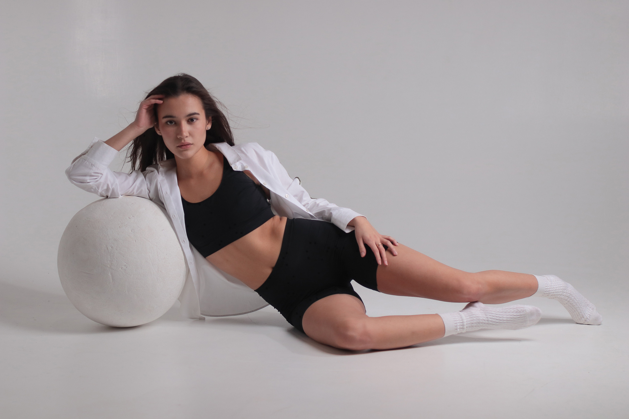 Модель в топике, лежащая на белом шаре в красивой позе