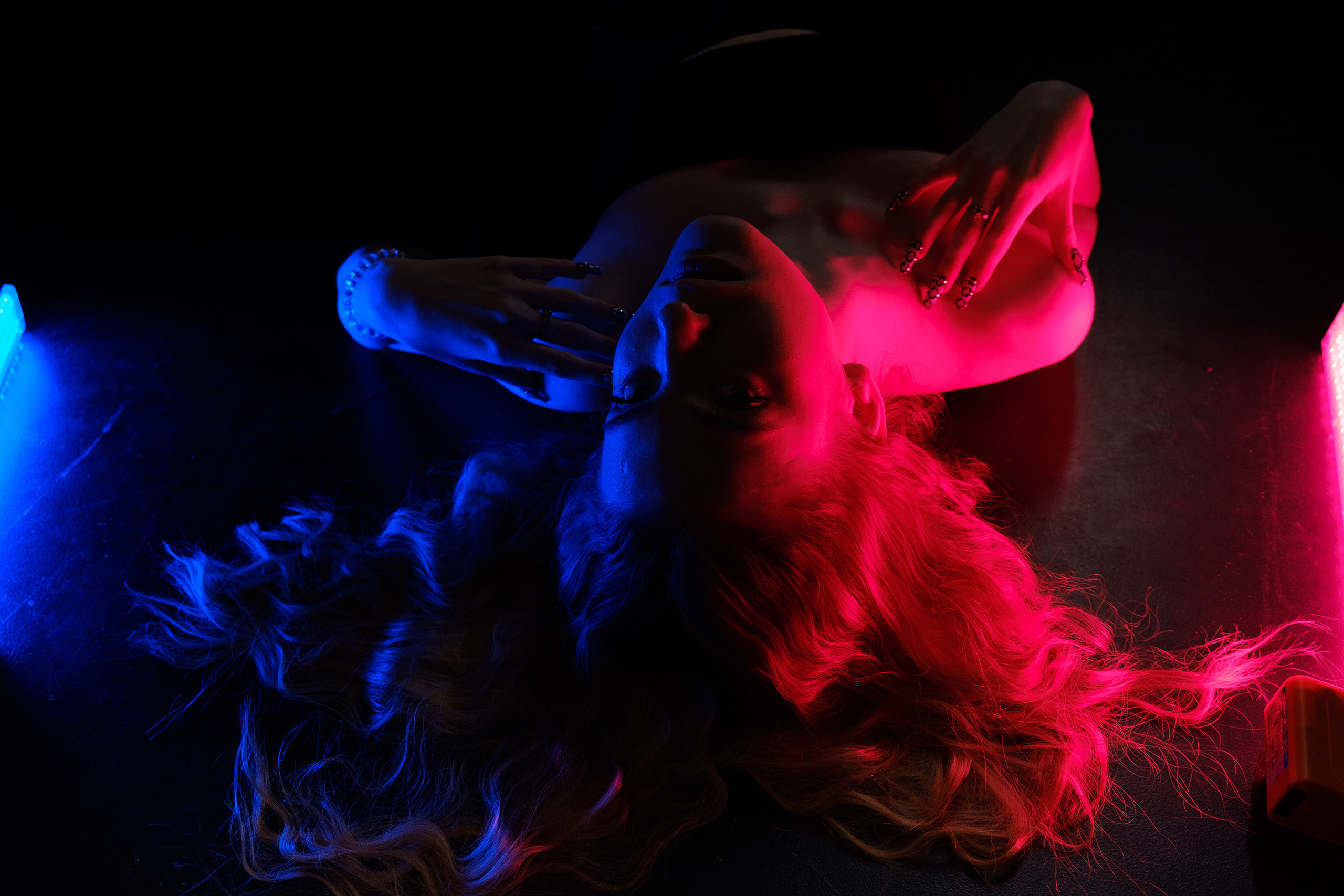 Девушка с распущенными волосами лежит на спине.Снято с двумя RGB источниками света.