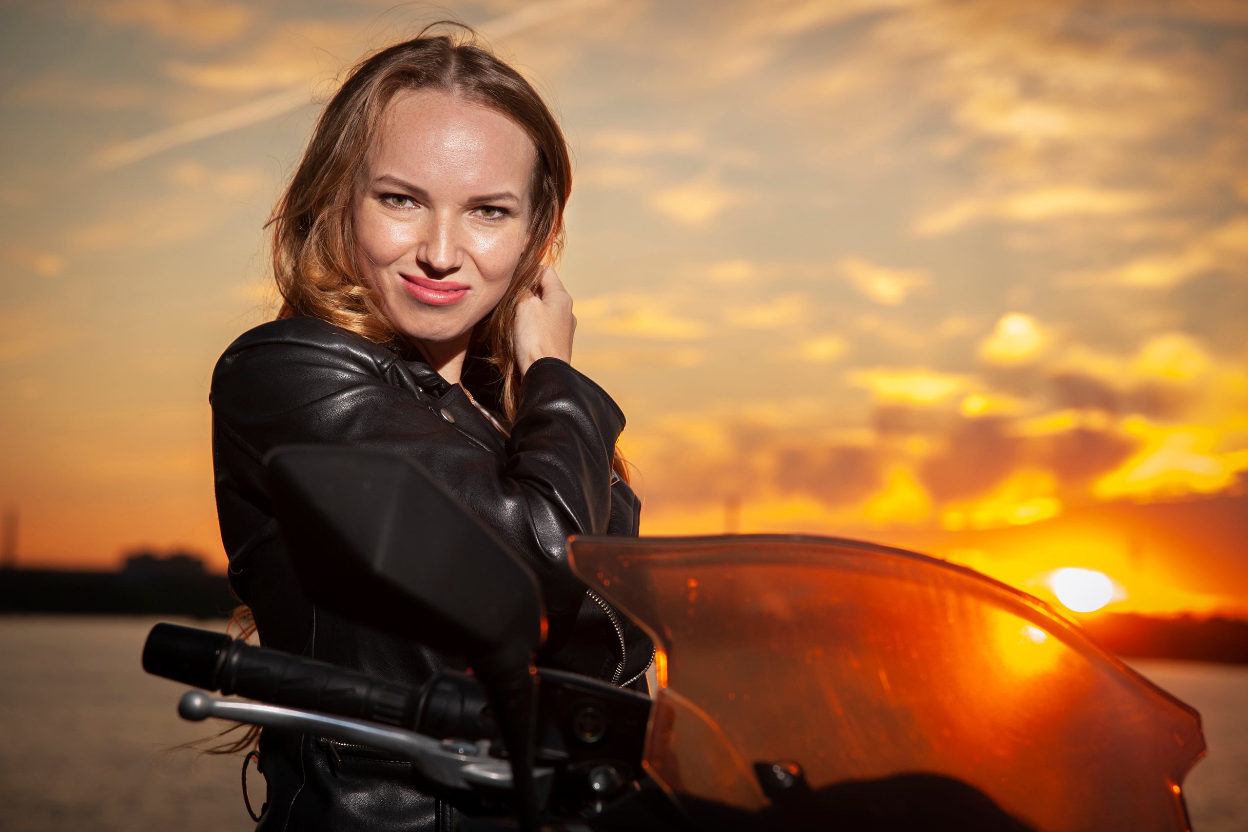 Девушка блондинка на байке на закате.